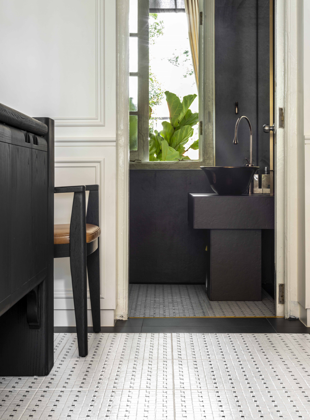 A glimpse into the powder room reveals dark fixtures set against crisp white surfaces, creating a striking contrast