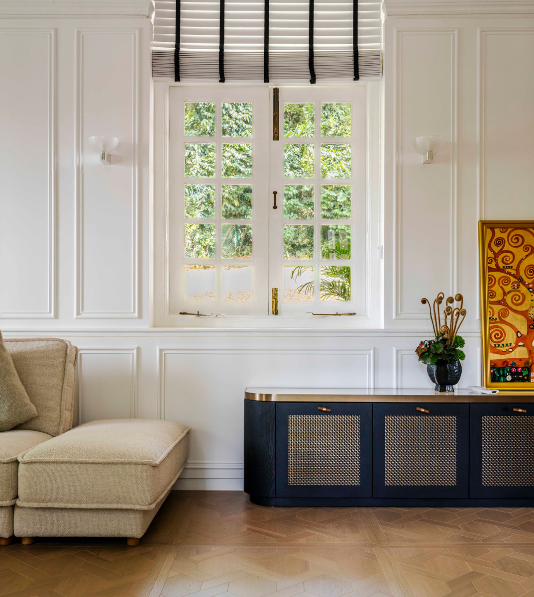 A panelled white wall forms a clean backdrop for a pairing of contrasts—an antique chest and a modern sofa
