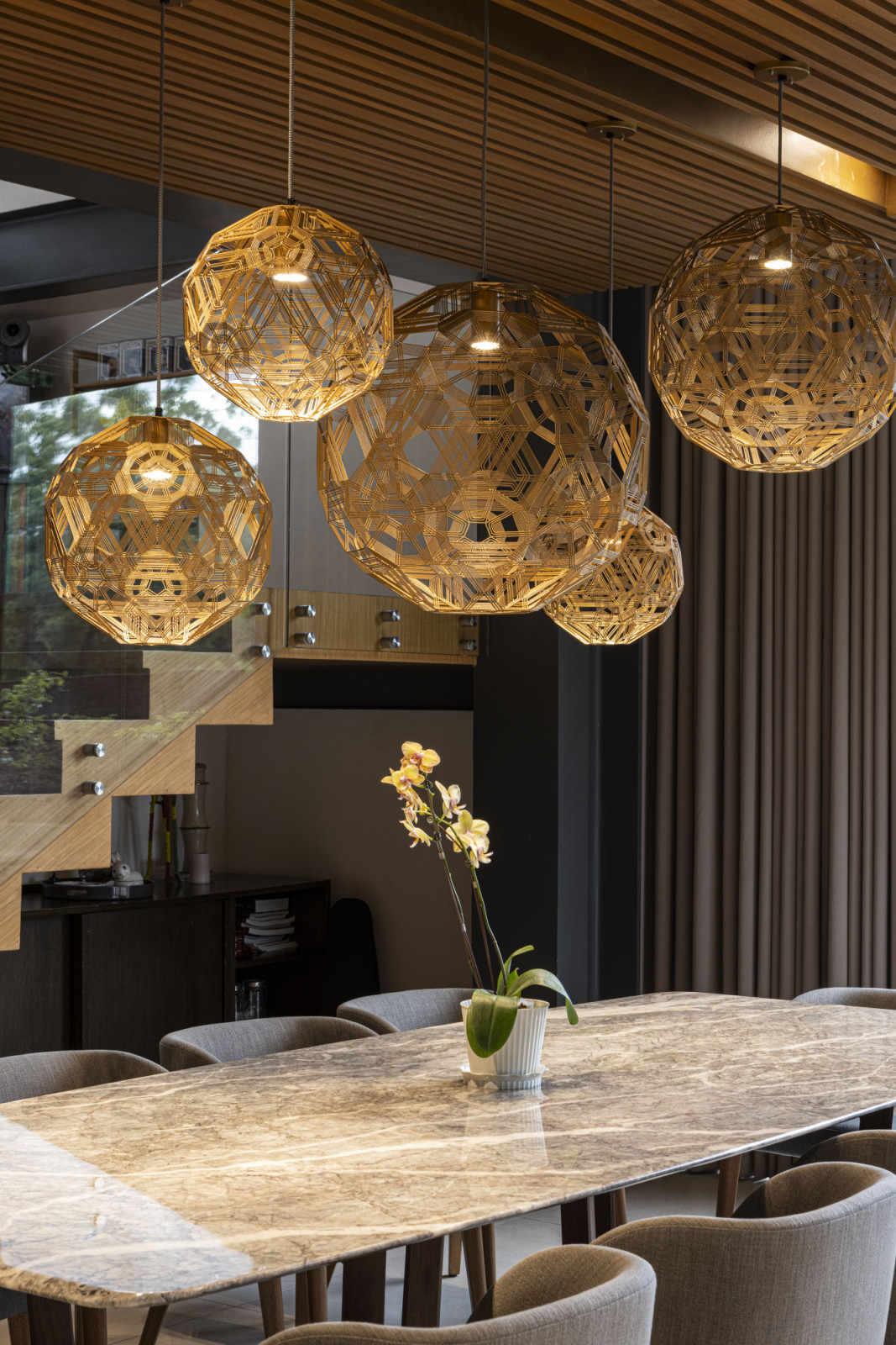 The dining room area of a vertical Filipino home in Manila, Philippines, designed by Barchan + Architecture, featuring a Schema lighting fixture