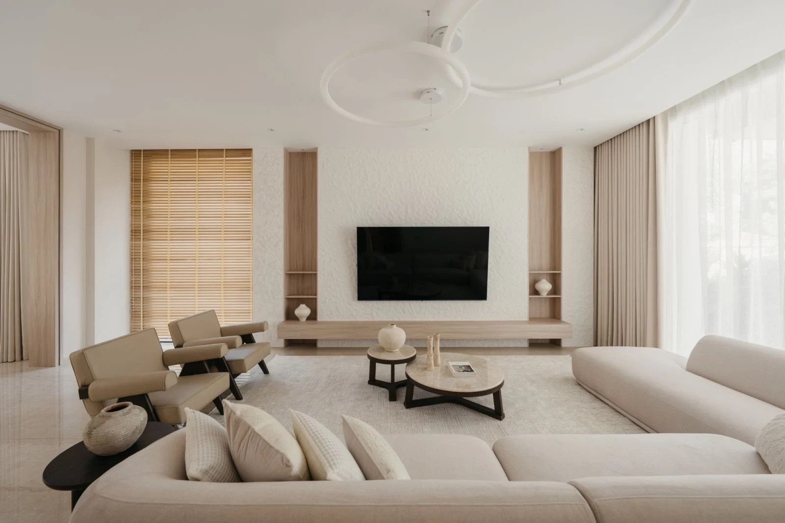 The living room features curved modular seating, bespoke wooden shelving and a textured white accent wall (Photo: BricksBegin)