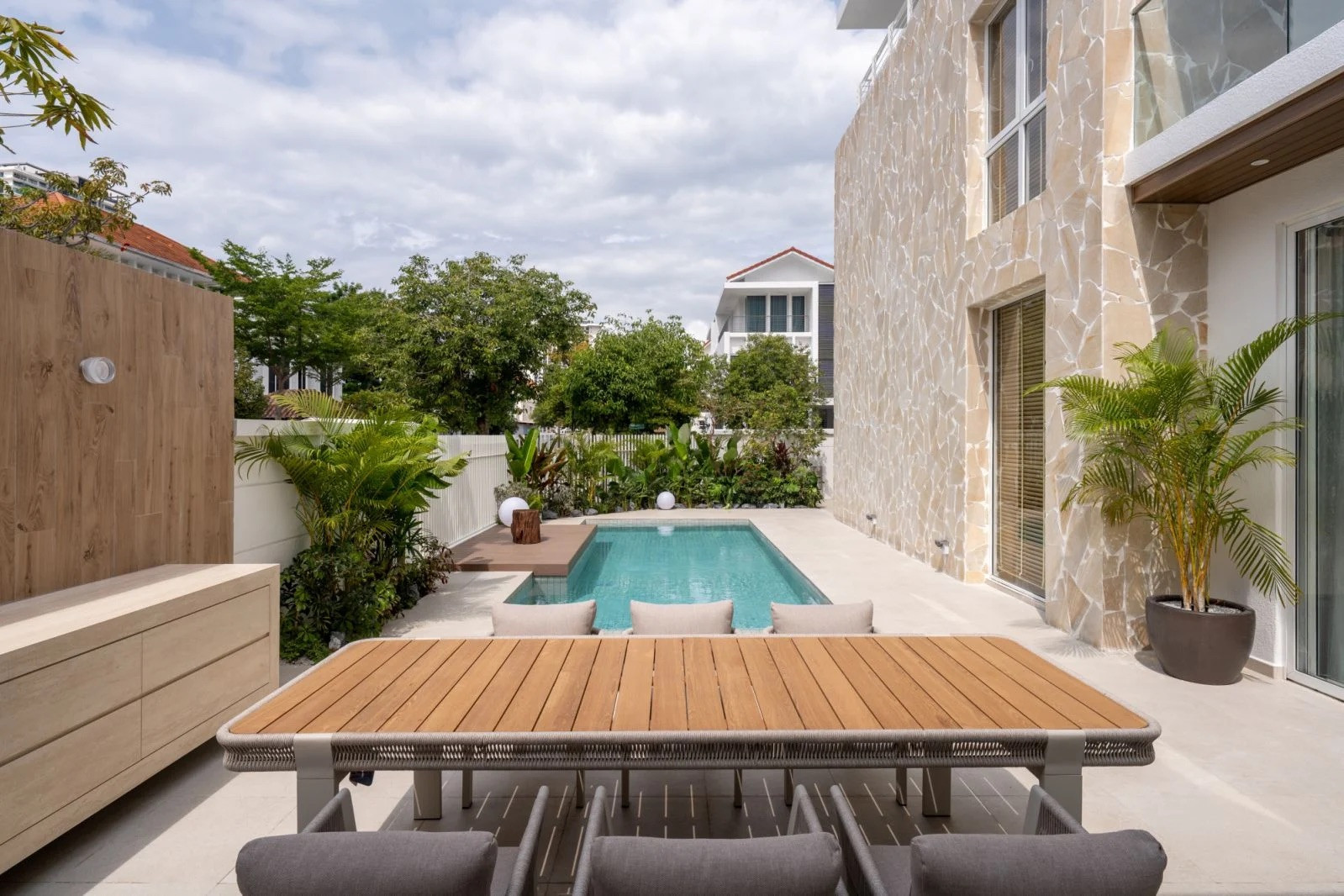 The pool terrace with integrated wooden deck and Sputnik Forest tropical landscaping (Photo: BricksBegin)