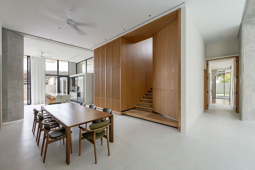 The dining area exemplifies the home’s zoning strategy, with warm timber elements encasing a stairway (Photo: BricksBegin)