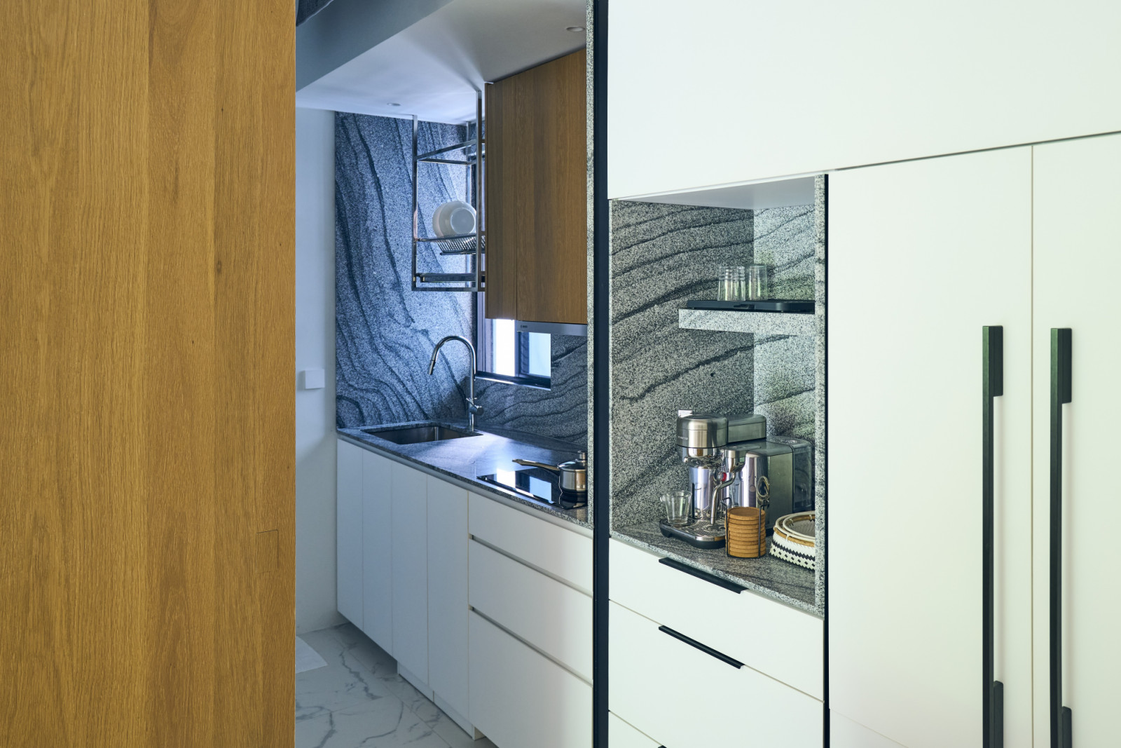 The separate wet kitchen is neatly concealed behind sliding glass doors to contain cooking fumes while maintaining a visual connection