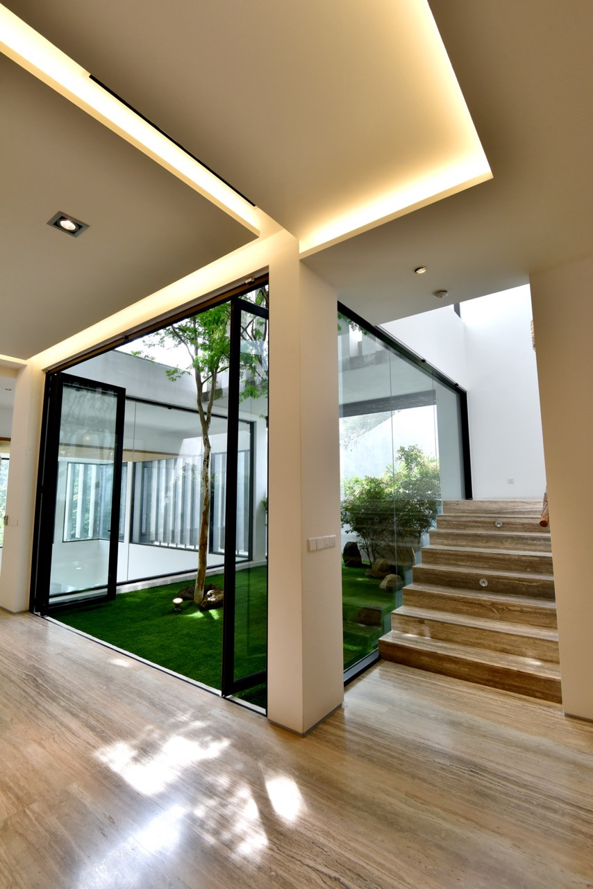 A view from the internal courtyard shows the timber staircase ascending to upper levels, with the lift shaft visible alongside the sculptural concrete elements