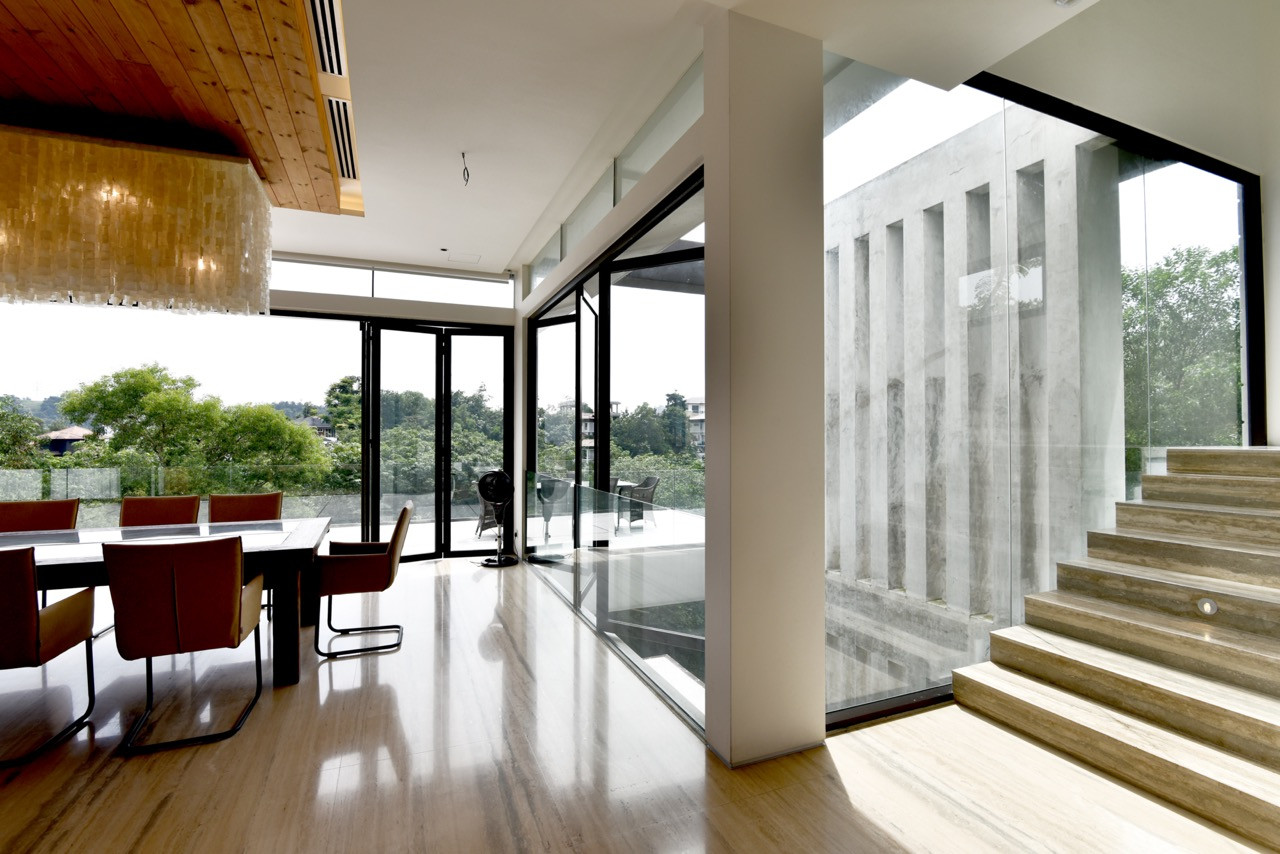 A view from the dining area shows the connection to outdoor terraces, with concrete fins visible outside providing privacy and solar shading.