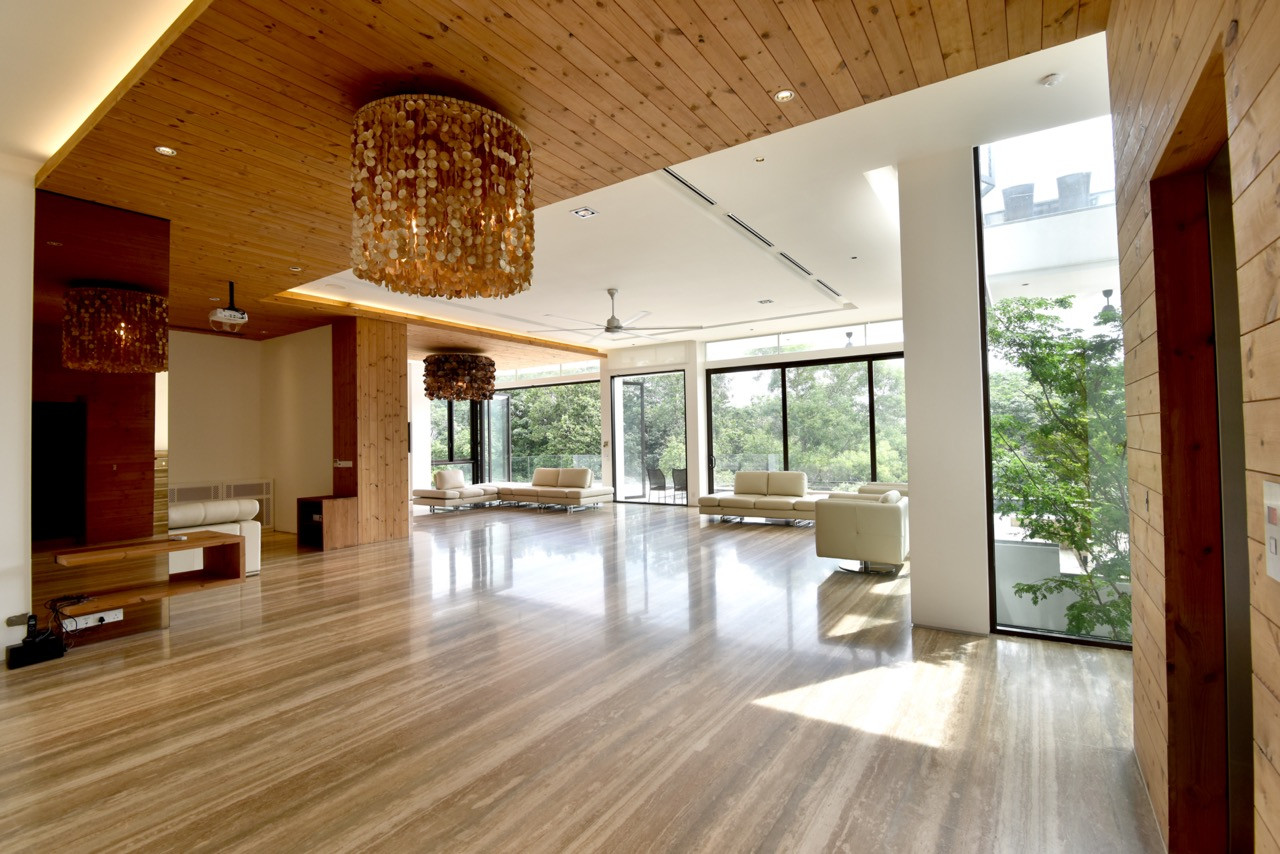 The dining area combines custom timber furniture with views across the forest, featuring integrated ceiling lighting that follows the angular roof geometry