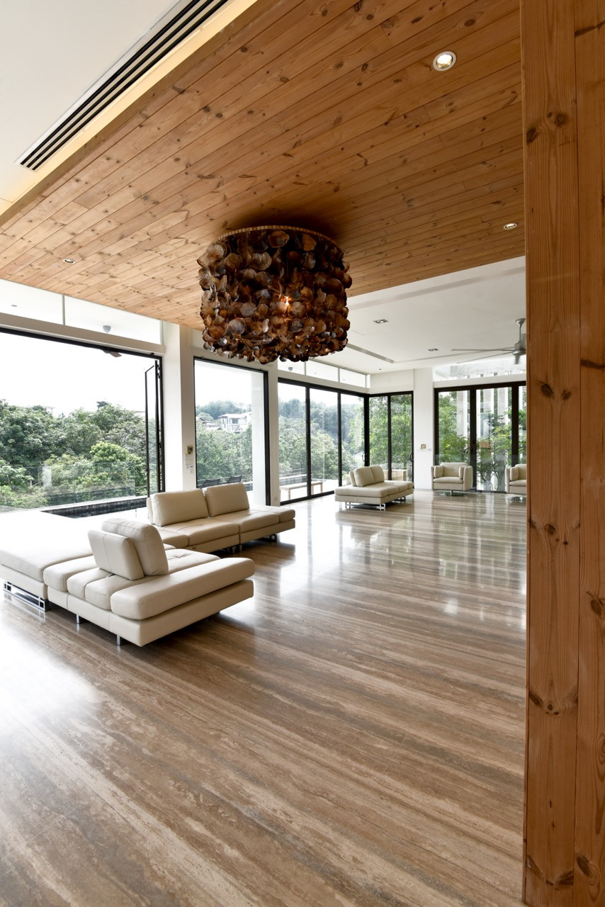 Timber ceiling planes define different zones within the open-plan living space, while travertine marble floors extend throughout the interior