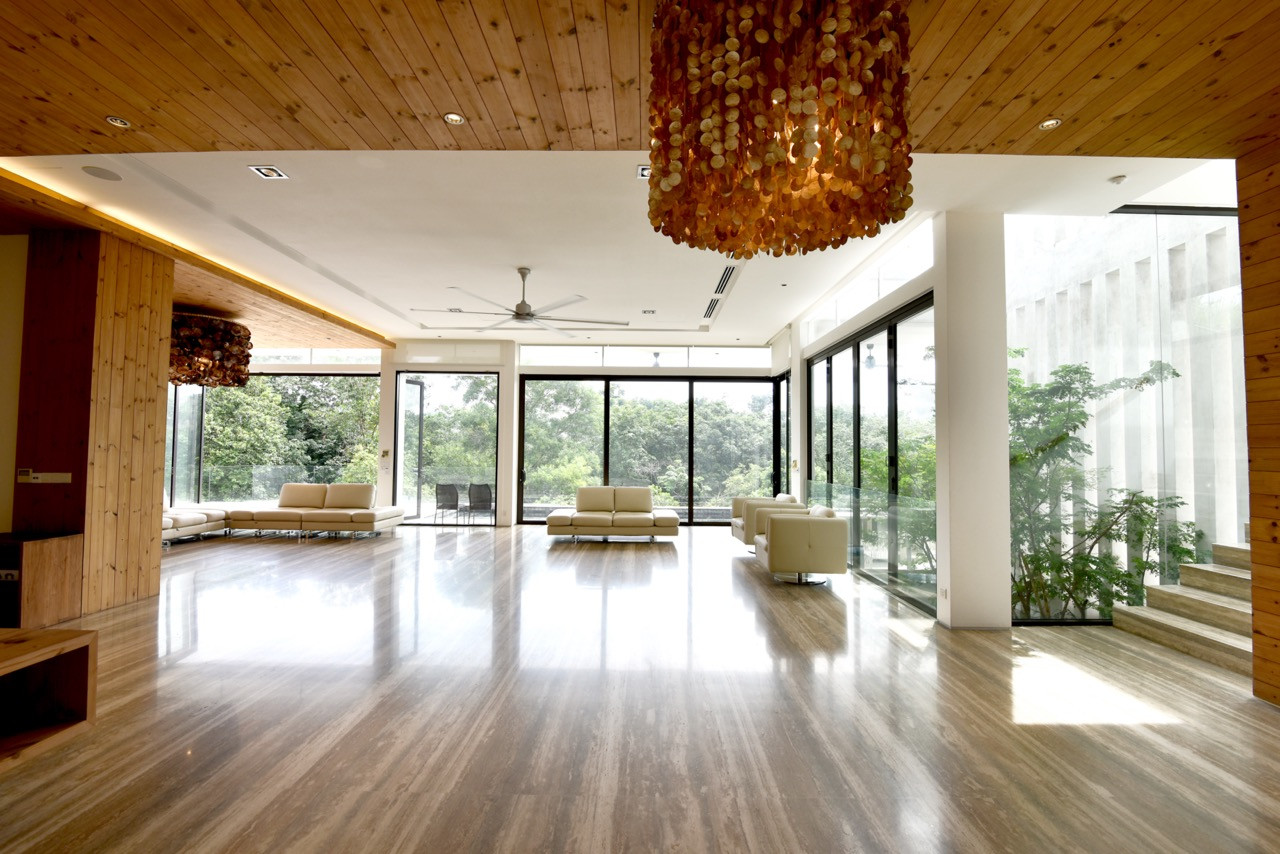 The main living area features timber ceilings with integrated lighting and shell-inspired chandeliers, opening directly to the pool terrace through floor-to-ceiling glazing.