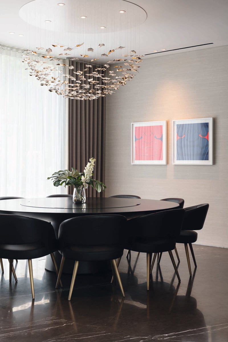 Statement lighting and artworks accent the otherwise monochromatic dining area