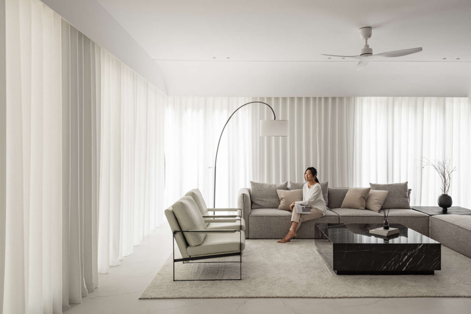 The main living area features modular grey seating and a black marble coffee table, with floor-to-ceiling curtains
