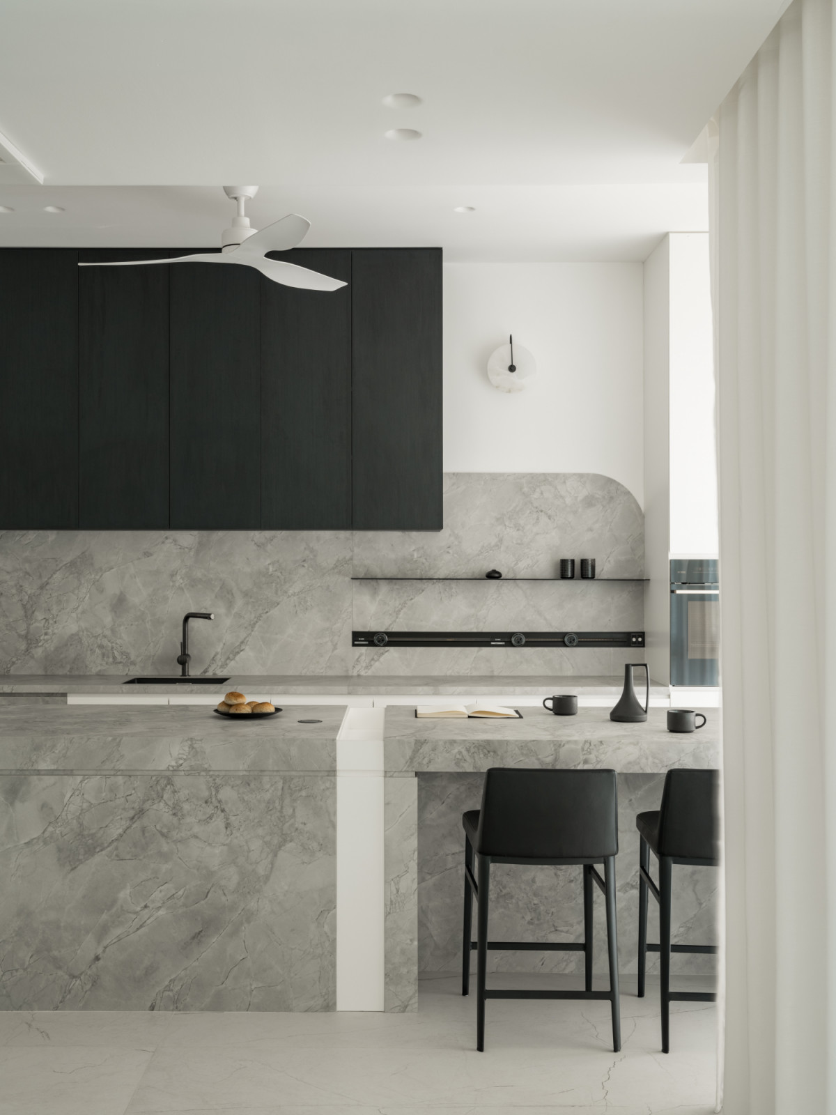 The kitchen island features sleek marble surfaces and minimalist cabinetry, with built-in storage that maximises functionality.
