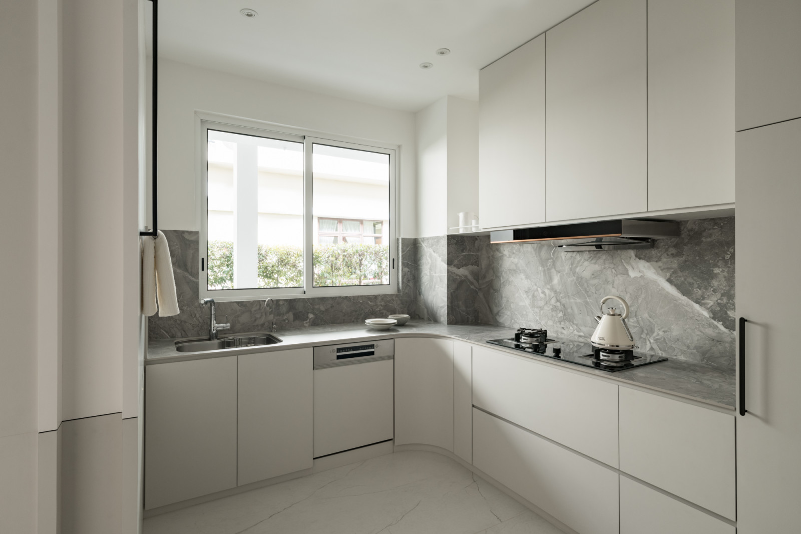 The compact wet kitchen layout maximises the available space with curved cabinetry and marble surfaces