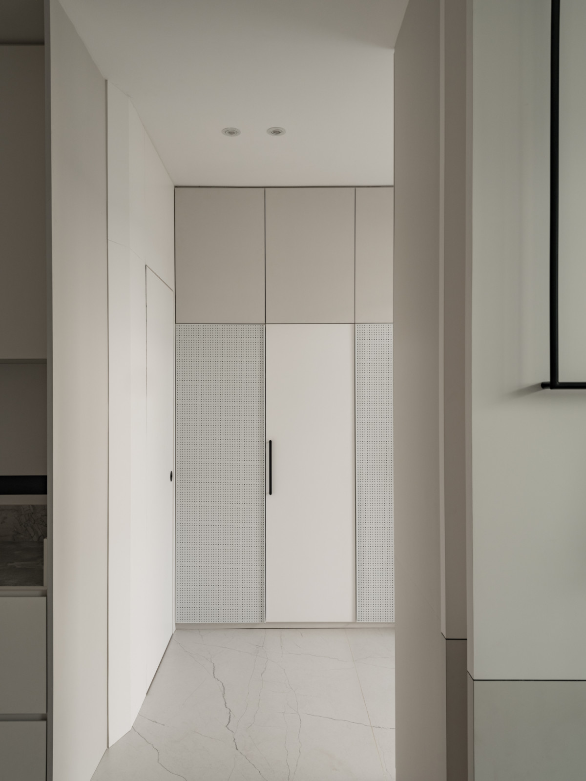 Built-in storage solutions feature perforated metal panels that provide ventilation whilst maintaining the clean aesthetic