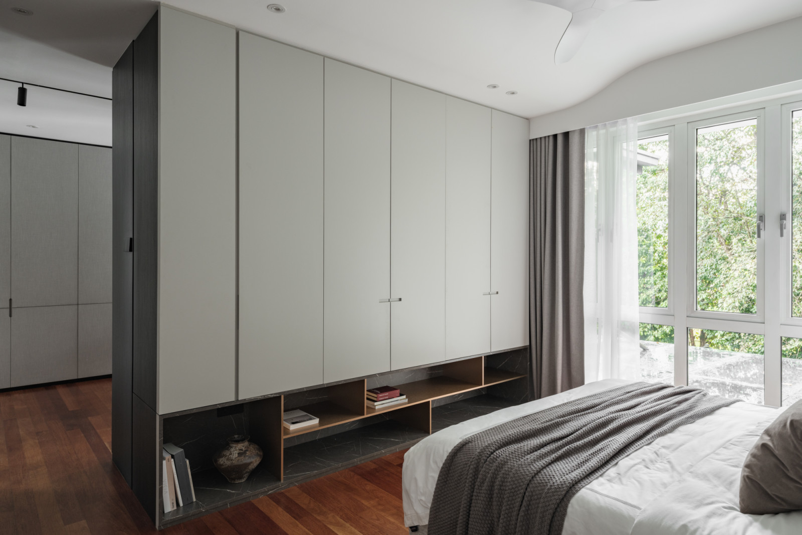 The master bedroom features floor-to-ceiling wardrobes with integrated open shelving, continuing the neutral-toned colour scheme