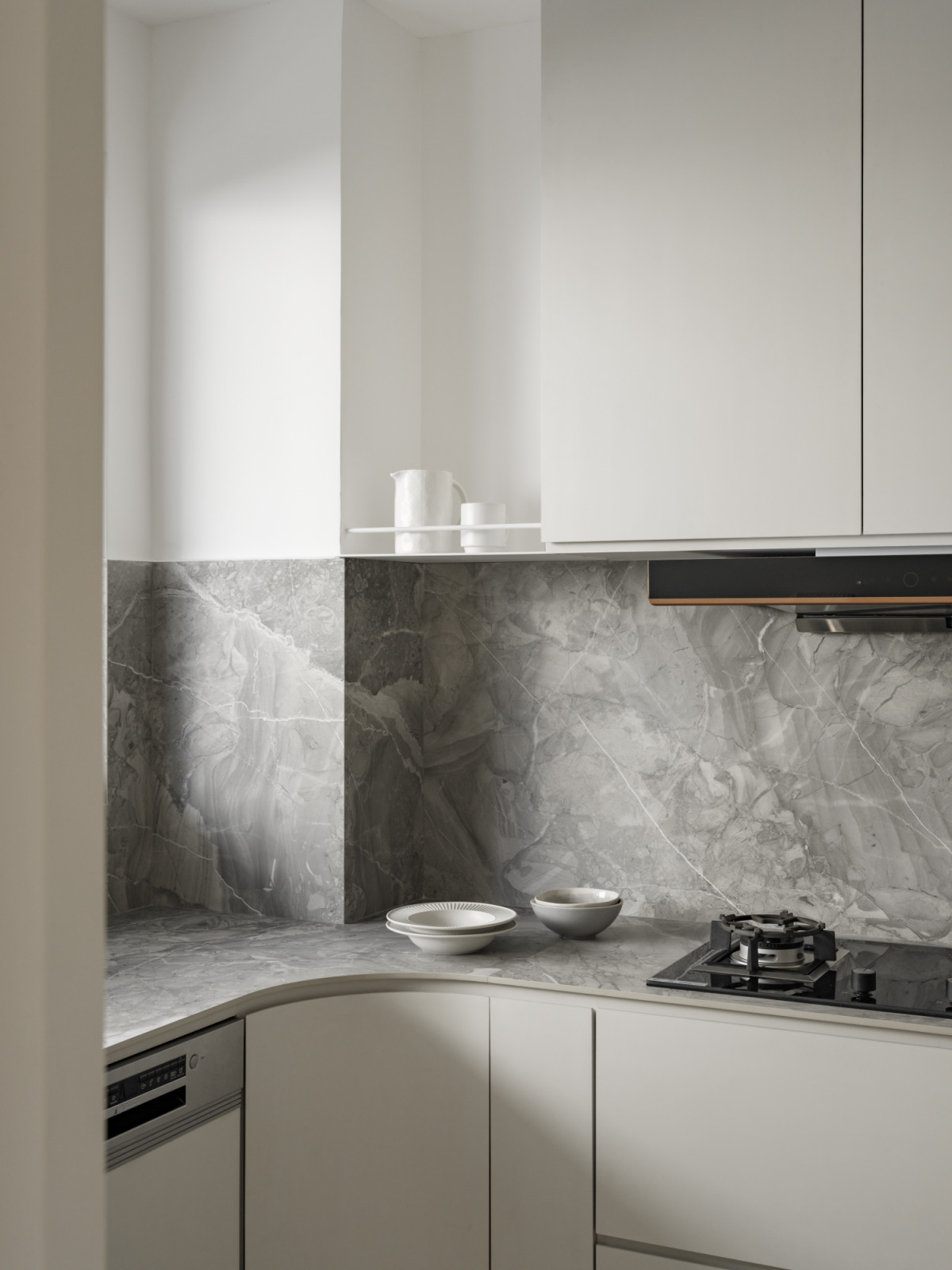 The wet kitchen showcases the cream marble surfaces with integrated gas cooking and sleek upper cabinetry
