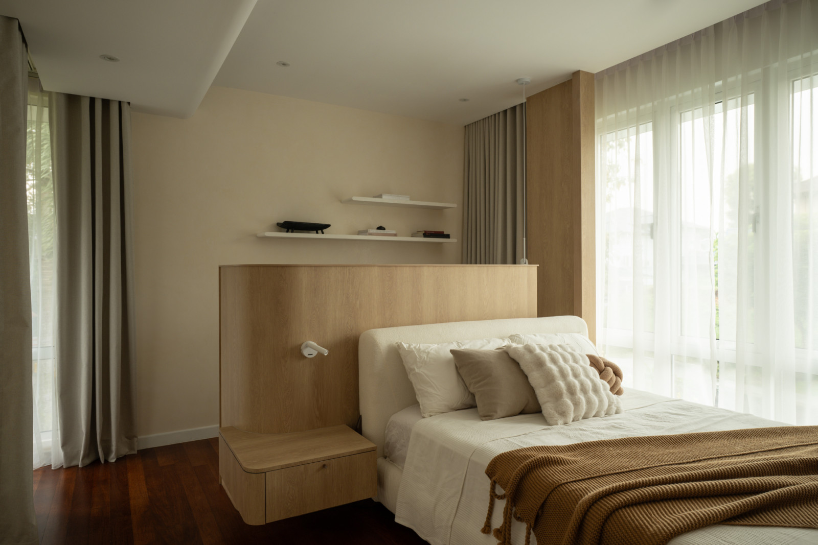 A guest bedroom features warm wood cabinetry and floating shelves