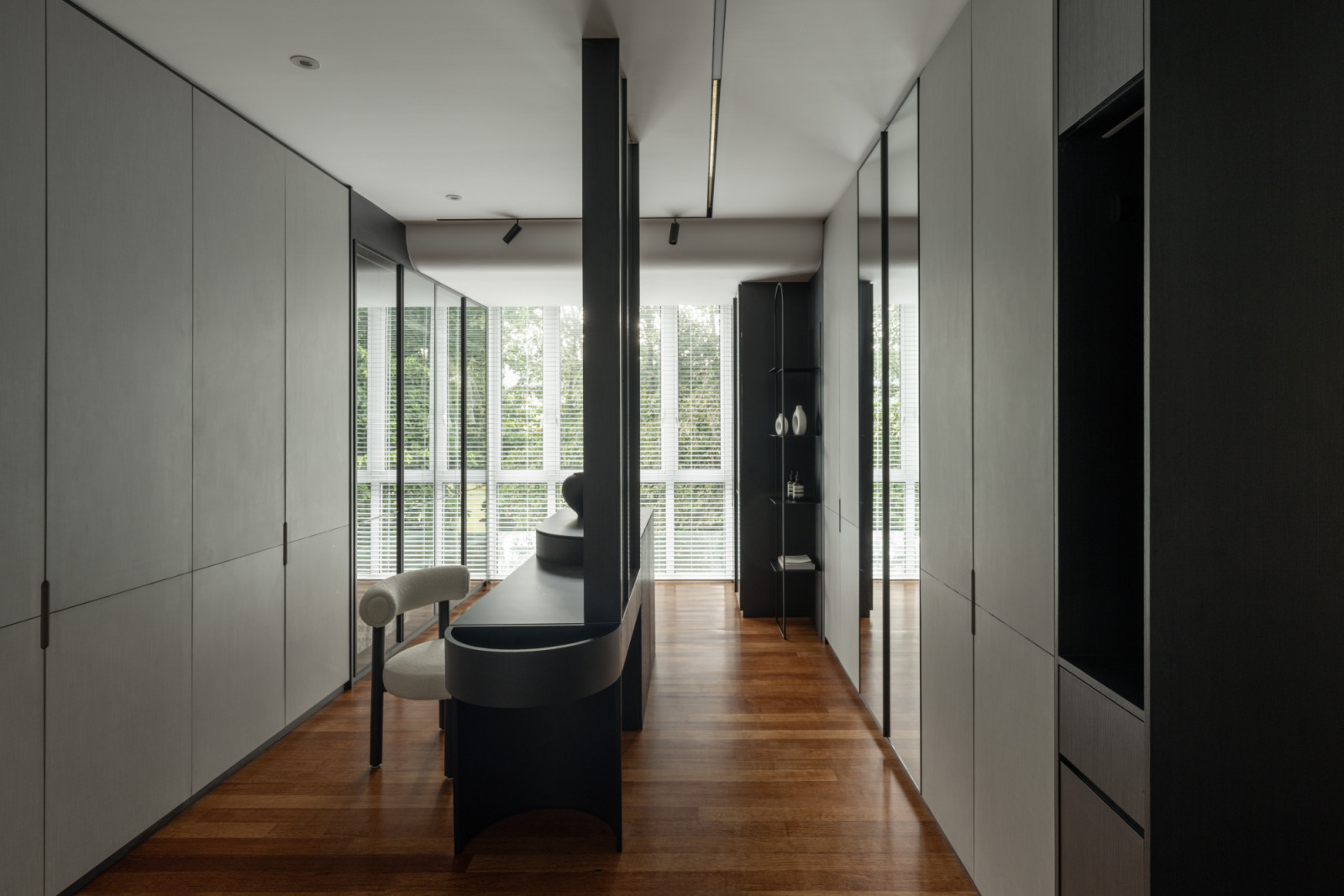 The master bathroom features floor-to-ceiling storage in neutral tones, with a black circular bathtub providing a focal point against the elegant wood flooring.