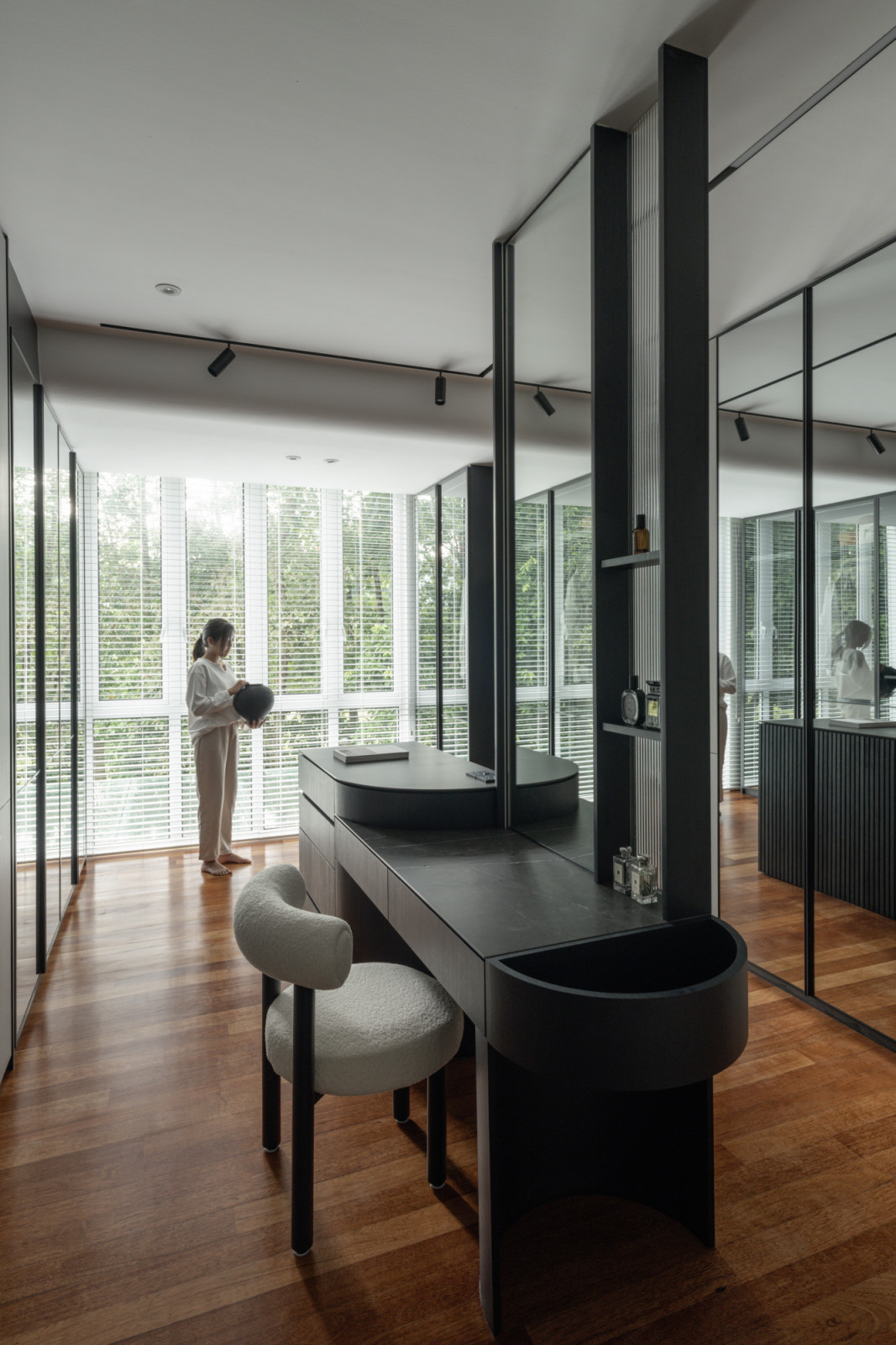 The master bathroom showcases the circular black bathtub positioned to capture garden views through the timber louvres