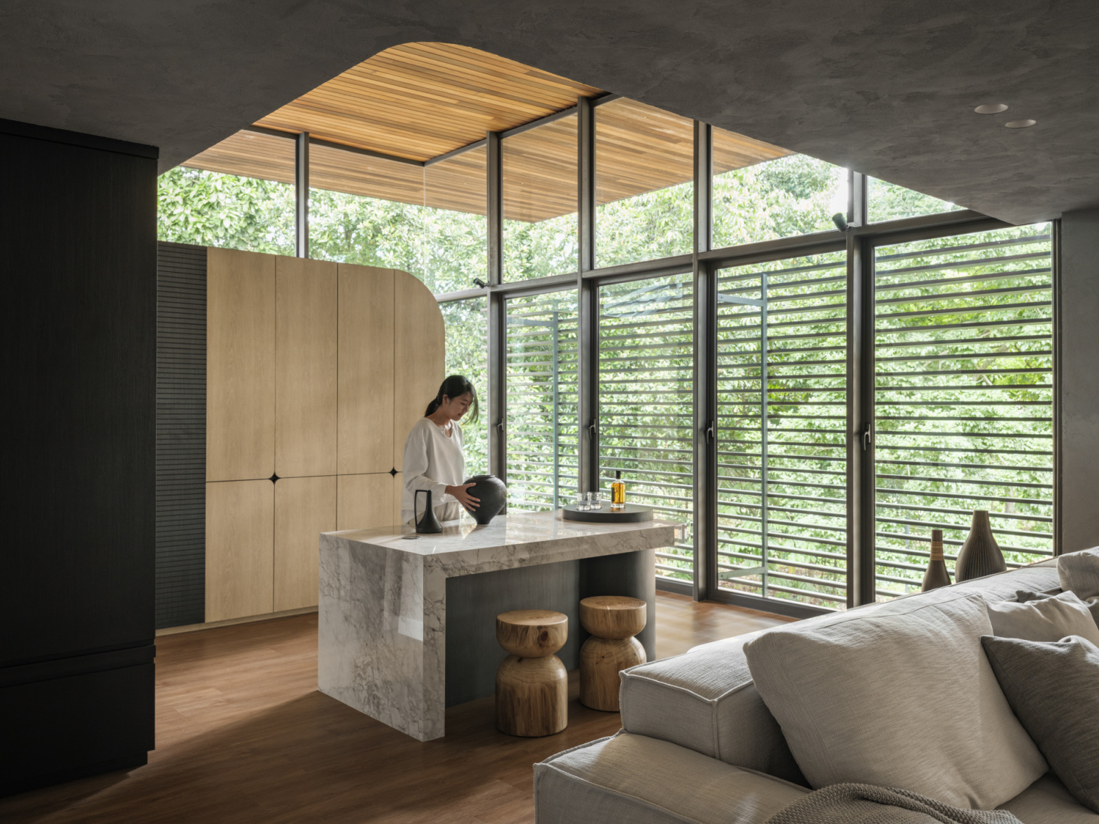 Floor-to-ceiling windows embrace the greenery outside with wooden louvres providing privacy