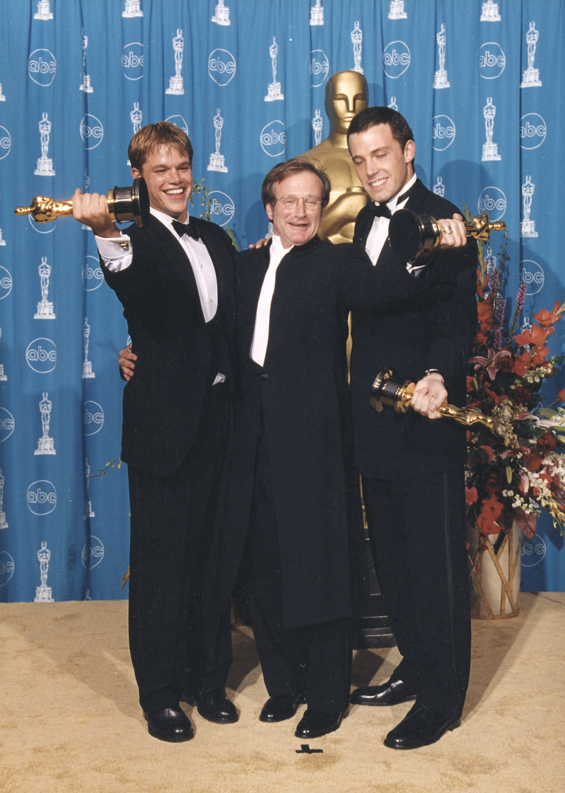 EDITORIAL USE ONLY: Matt Damon, left, and Ben Affleck, right, winners, Writing (Screenplay Written Directly for the Screen) (GOOD WILL HUNTING), and Robin Williams, winner, Actor in a Supporting Role (GOOD WILL HUNTING), hold their statuettes backstage at the 1997 (70th) Academy Awards ceremony. Photographer's stamp on verso. (Photo by Long Photography/The Academy via Getty Images)