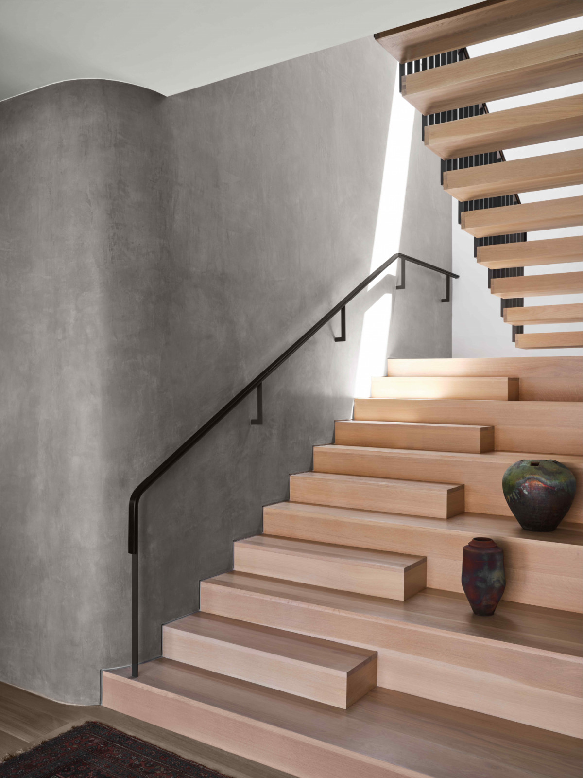 A Light oak wide plank stairway against grey plaster wall