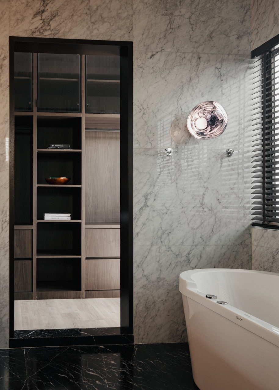 The master bathroom combines white Carrara marble with custom built-in storage, featuring a Philippe Starck oval freestanding bathtub and Tom Dixon Melt Mini wall lamps