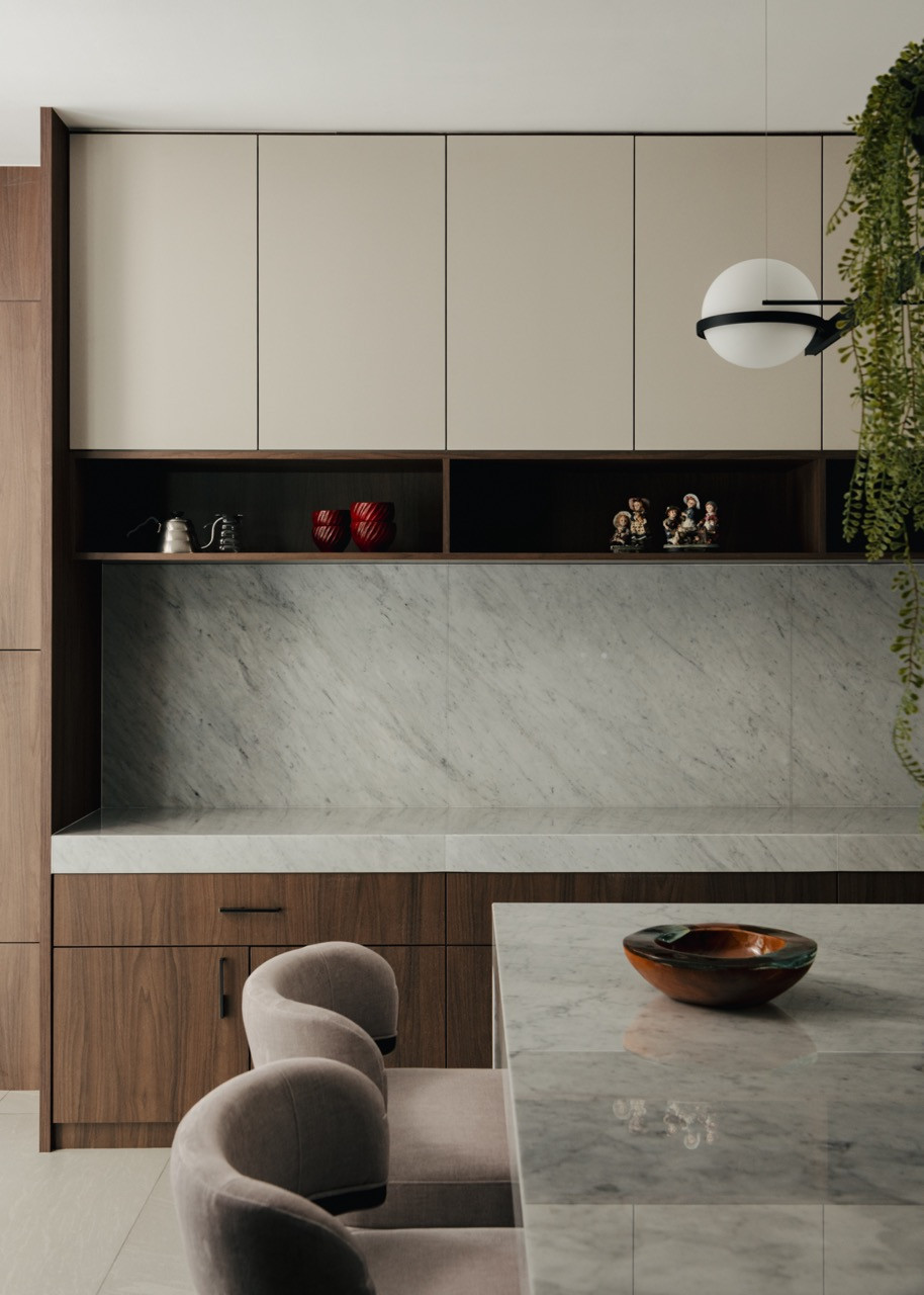 The kitchen features a restrained material palette, highlighted by a white Carrara marble backsplash and timber cabinetry,