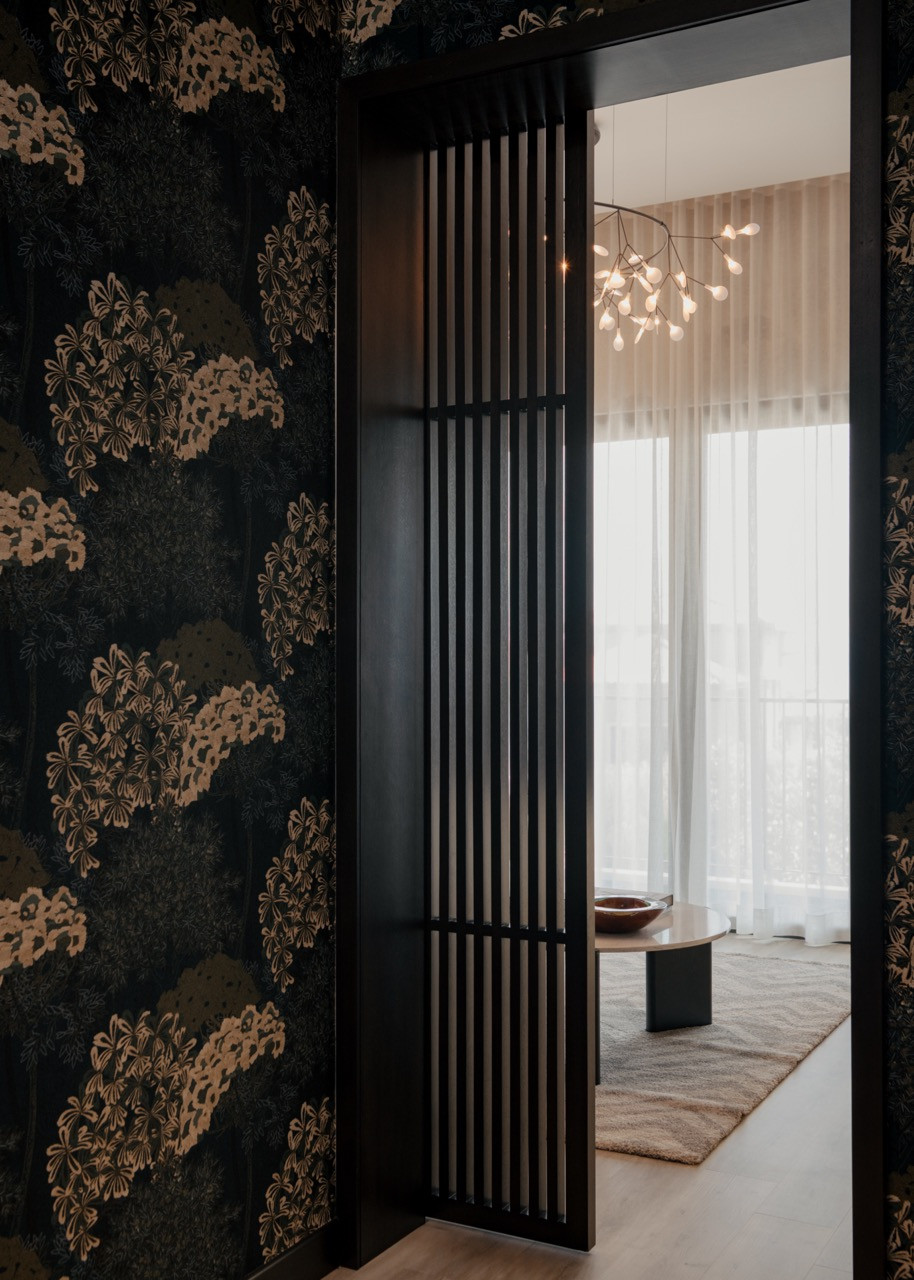Dark floral wallpaper creates a dramatic contrast in this bedroom space, leading to the master bedroom lounge area, where the Heracleum III pendant light by Moooi provides sculptural lighting