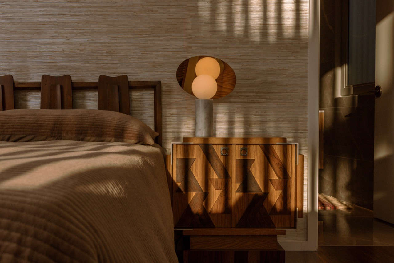 The primary bedroom features vintage 1970s nightstands from Chairish, Stark wallpaper, and a Pablo table lamp