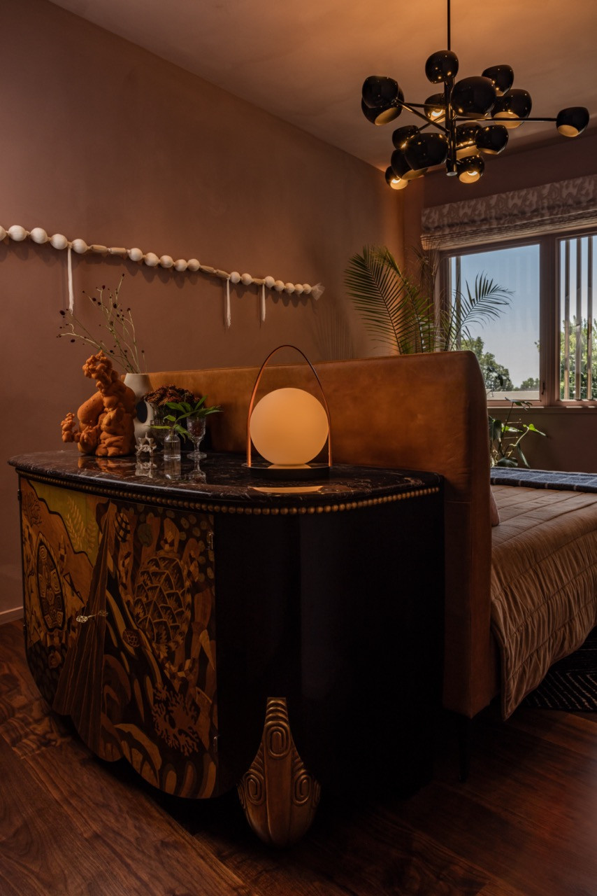 The guest bedroom centers on a 1980s Italian marquetry chest with inlaid turtle scenes in mustard, terra cotta, and chartreuse, topped with plum marble and ornate gold legs