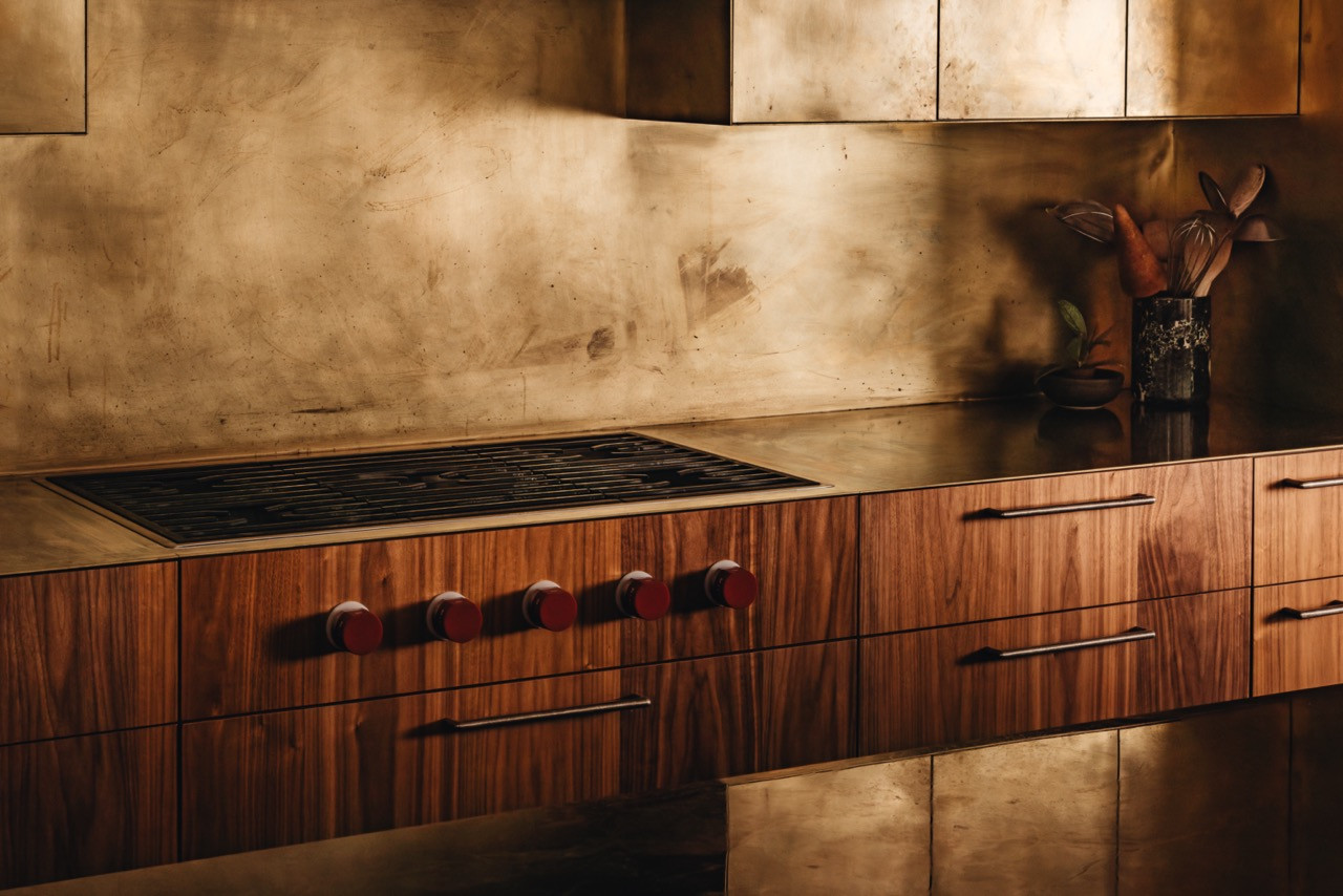 Kitchen cabinetry includes walnut millwork with brass hardware, concrete backsplash, and integrated Wolf appliances