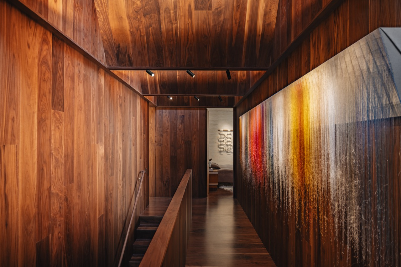 The walnut-clad upper level hallway serves as a top-lit gallery connecting bedrooms, studio, and office spaces