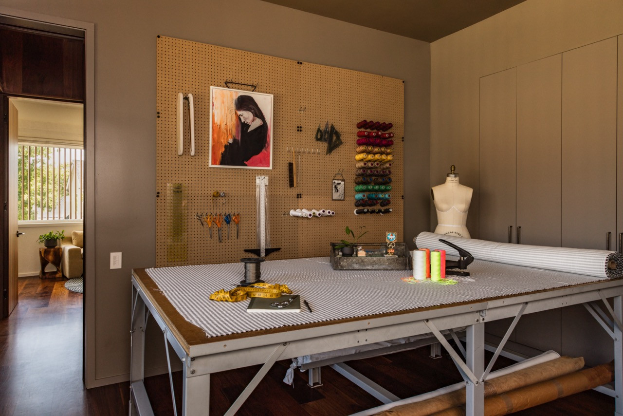 Feldkamp's design studio contains a professional cutting table, pegboard tool organisation, colourful thread storage, and a Wolf dress form