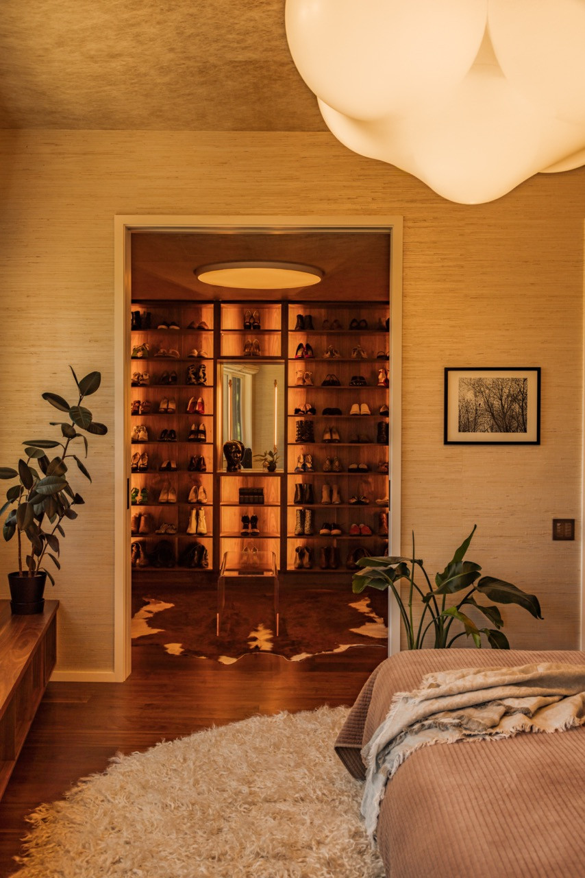 The primary closet features an oculus light by Prudential, Juniper sconces, and custom walnut millwork with a Homary bench.