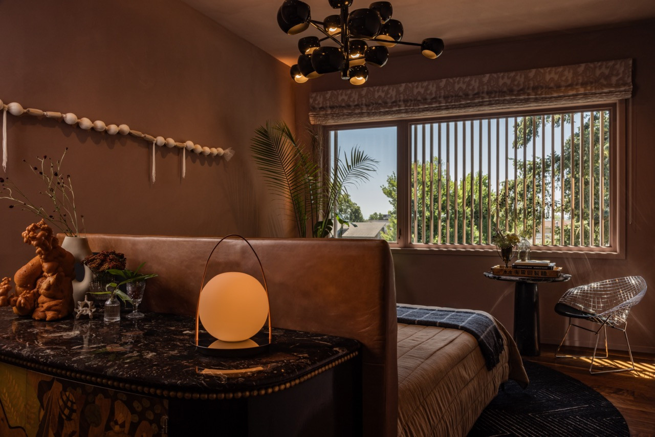 The guest bedroom centres on the 1980s Italian marquetry chest with plum marble top and ornate gold legs that inspired the room’s desert-toned palette in mauve limewash paint