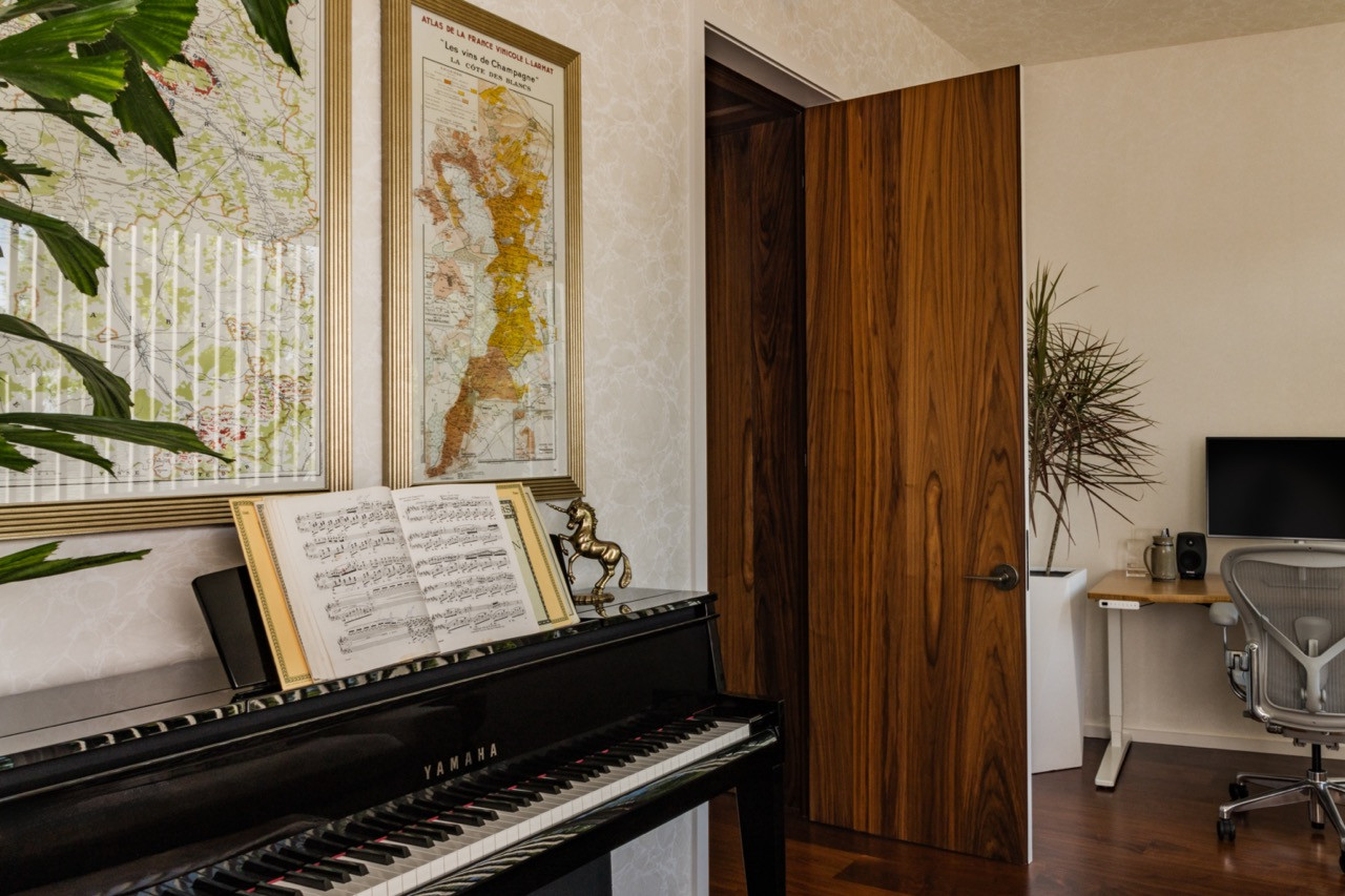 The office includes a Yamaha piano, Wallquest wallpaper, an Uplift desk, a Herman Miller chair, and a vintage coffee table from Chairish