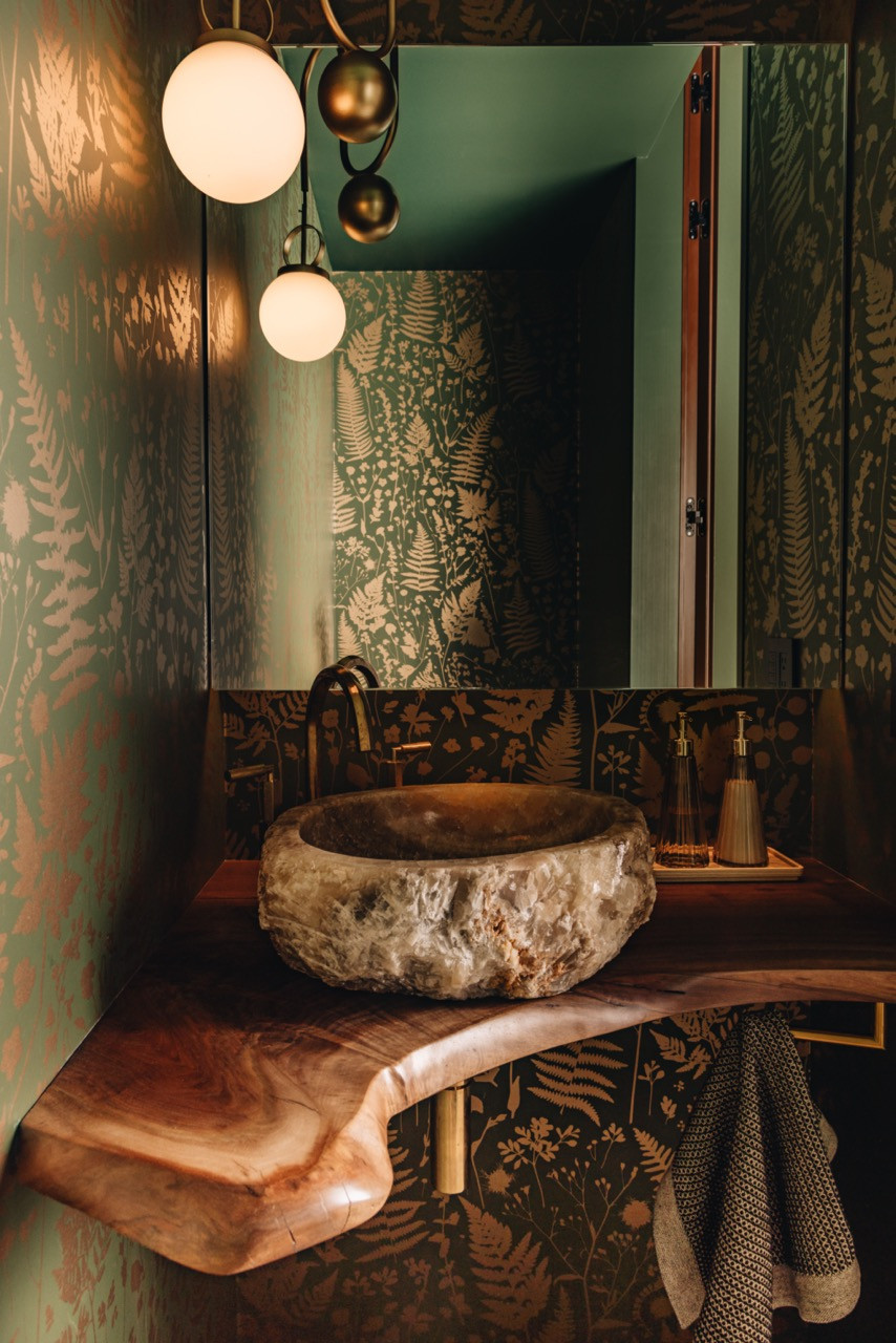 The powder room shows the complete botanical wallpaper by Makelike surrounding the custom onyx vessel sink on live-edge walnut counter with brass fittings