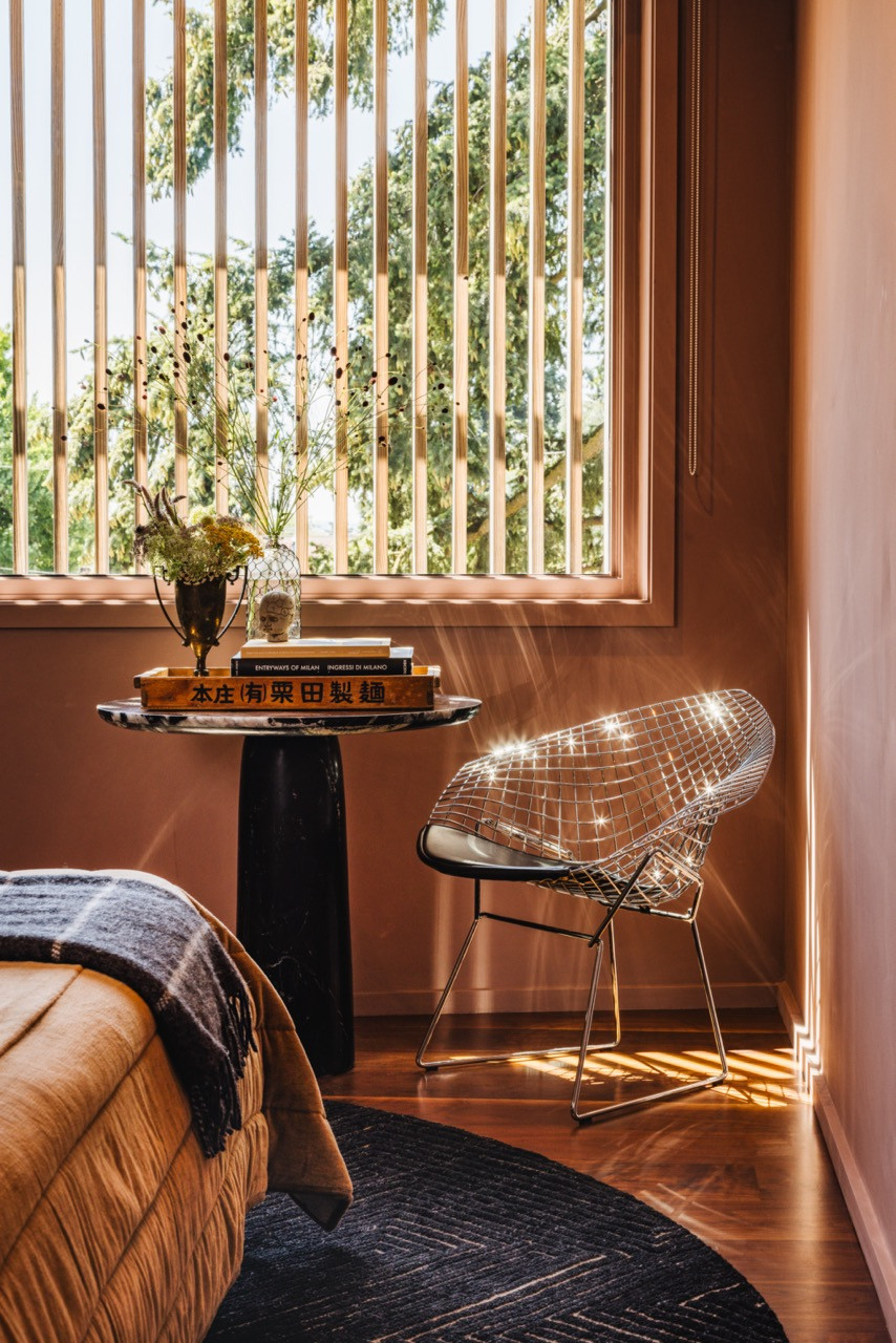 The reading nook features a Tiago Curioni chair sourced from 1stdibs, a Souda Brooklyn side table, and motorised shades that filter light while maintaining views of the garden.