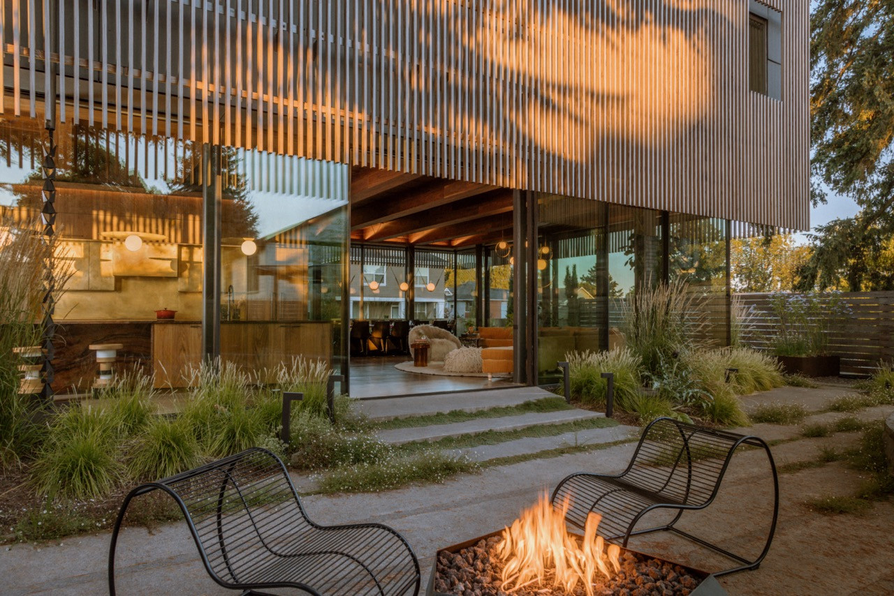 The backyard features a custom steel fire feature by Boy Boy, Bend Goods patio chairs, and a pergola with disco ball that casts light into the kitchen