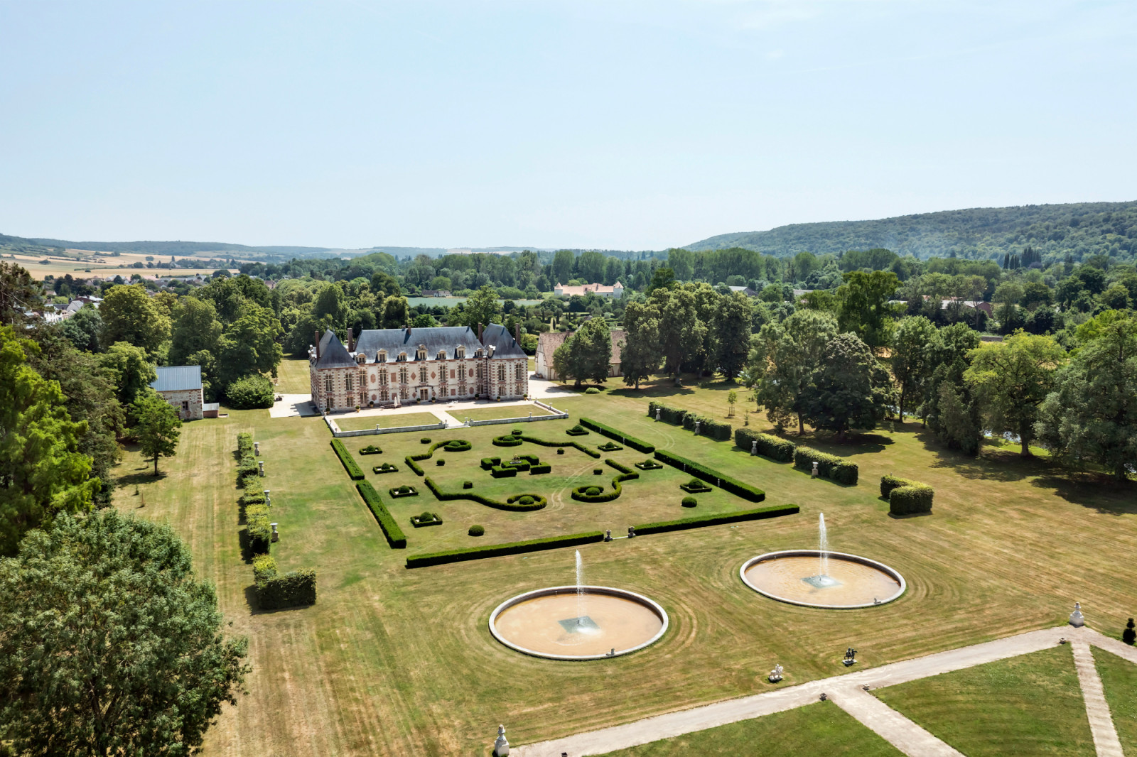 Panoramic view of the Normandy château set in the Eure Valley, showing the estate’s rural location one hour from Paris, with its centennial trees and landscaped grounds