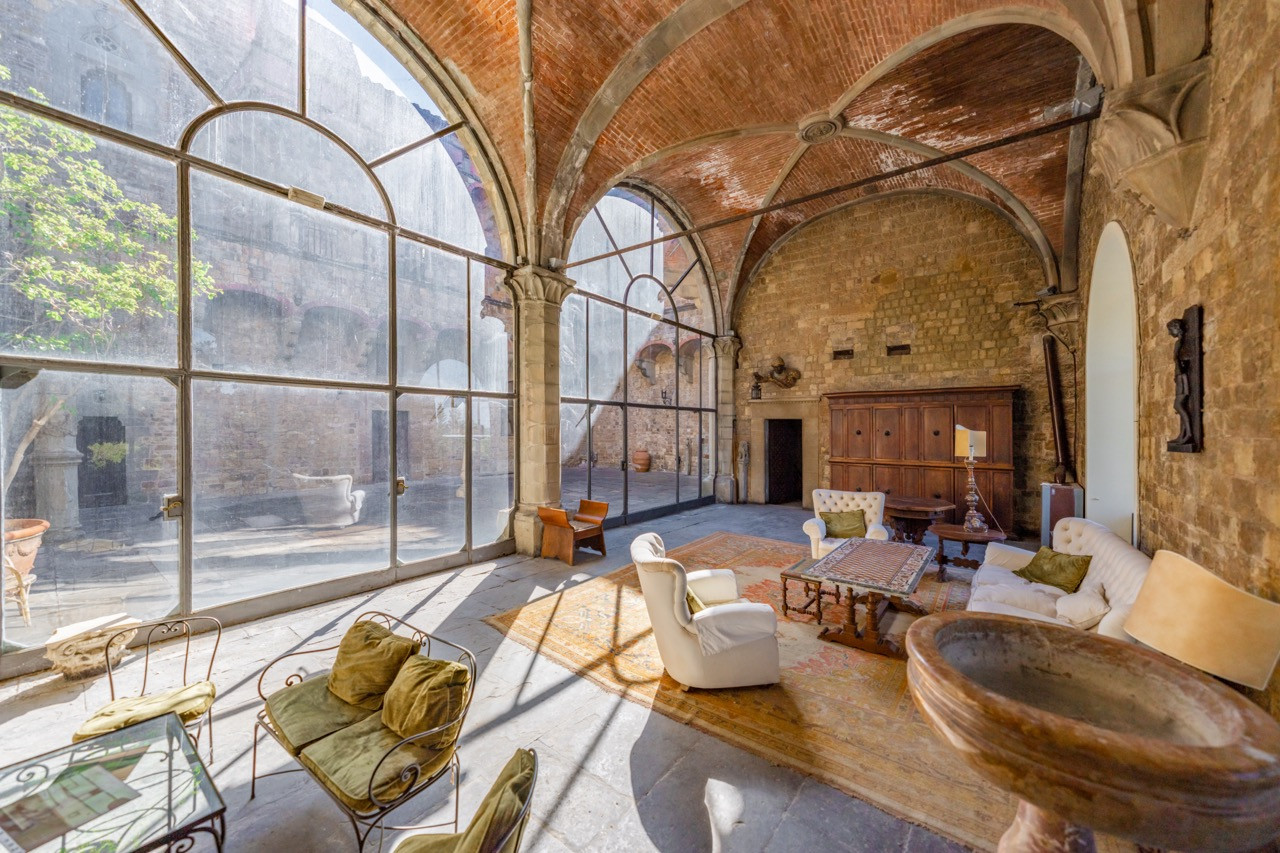 nterior hall of Castello di Vincigliata featuring large arched windows and medieval stonework, part of the castle's 985 square meters spanning multiple floors around the central courtyard