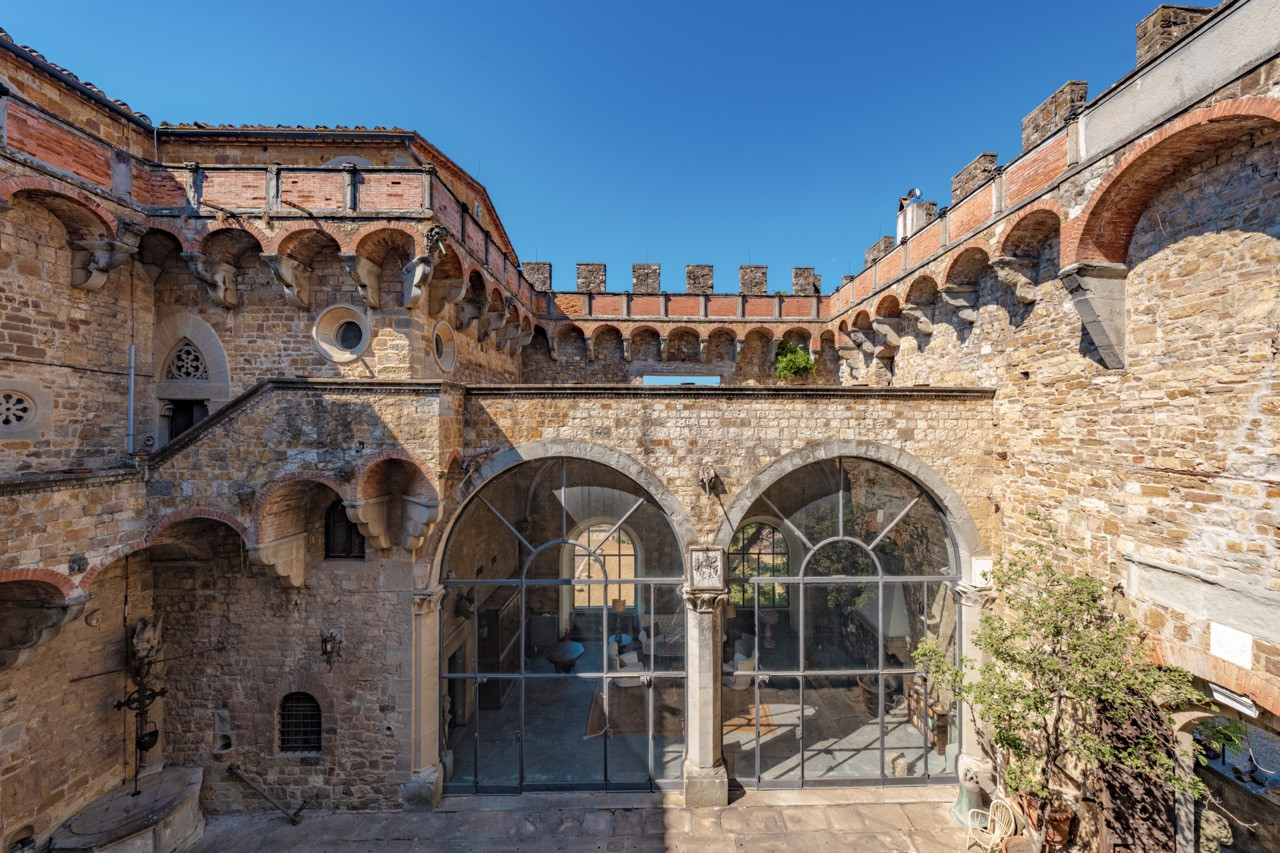 Defensive walls and glass installations at Castello di Vincigliata showing how this historic European castle adapts medieval architecture for modern use while maintaining its thousand-year heritage
