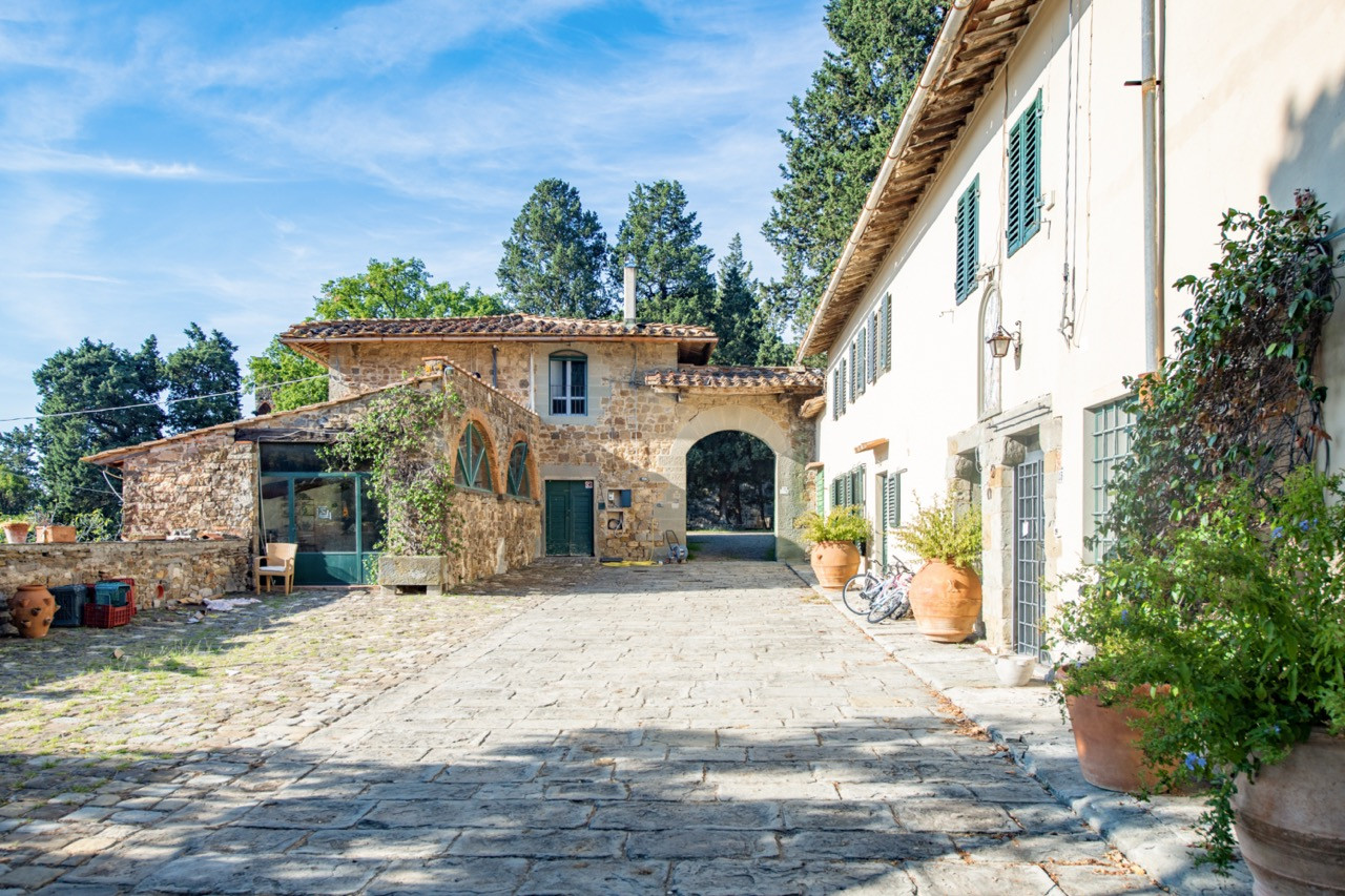 Courtyard area between estate buildings at Castello di Vincigliata, showing the stone paving and traditional Tuscan architecture that complements the main historic European castle structure