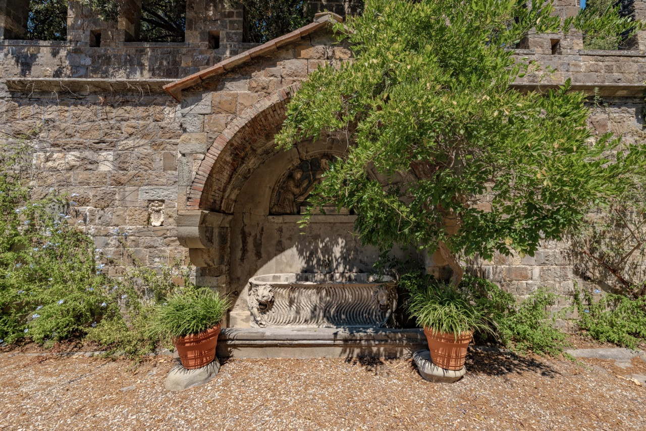 Ancient stone fountain within the castle grounds at Vincigliata, featuring carved stonework typical of the medieval elements preserved throughout this historic European castle property