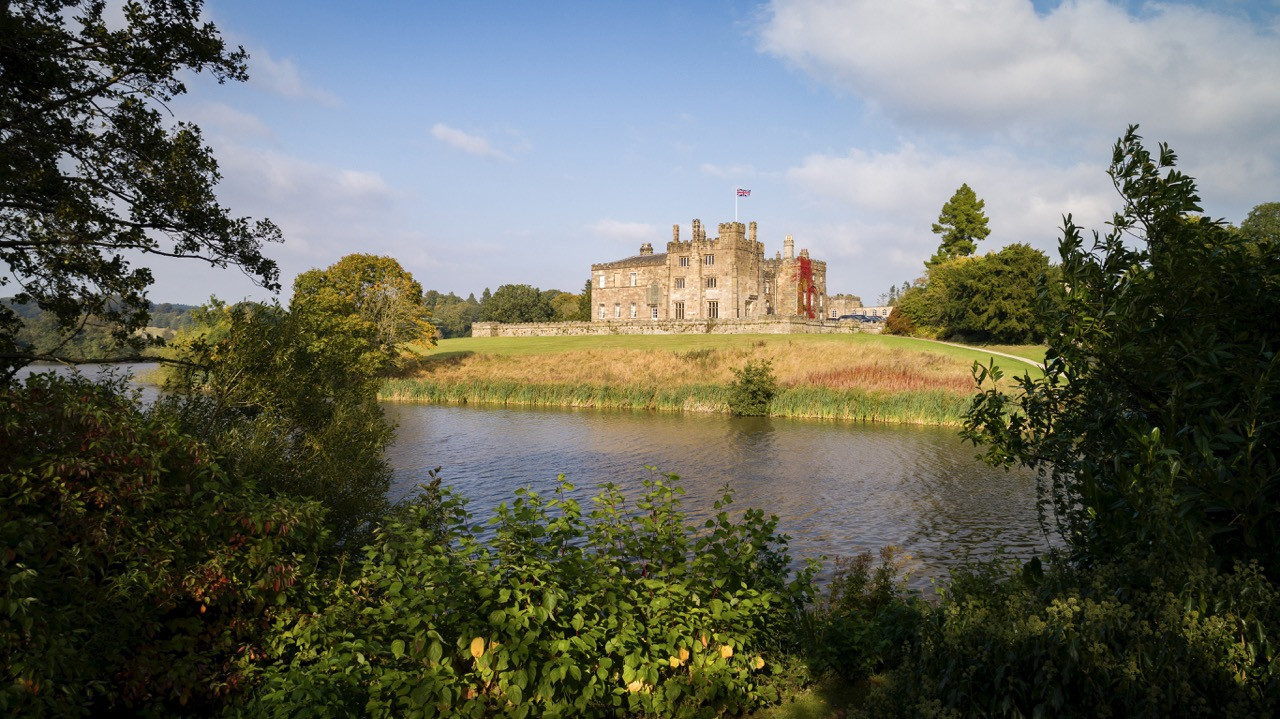 Ripley Castle, viewed from across the lake, showcases the Grade I listed 14th-century structure with its Georgian rebuilding, set within 165.59 acres of registered parkland at this historic European castle, which has been owned by the same family for over 700 years.