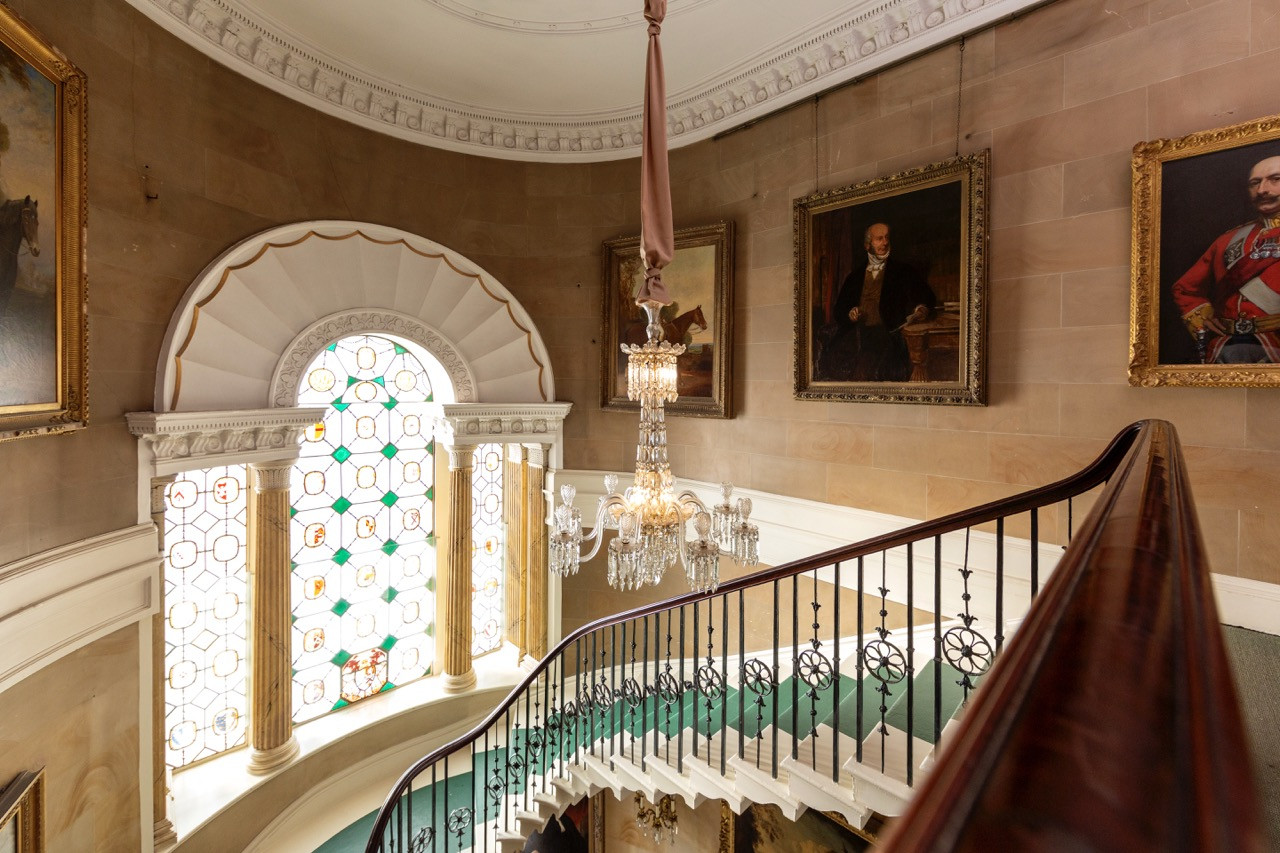 The magnificent cantilevered staircase at Ripley Castle, with an armorial stained-glass window, one of the castle’s most remarkable architectural features, from the Georgian reconstruction of this historic European castle