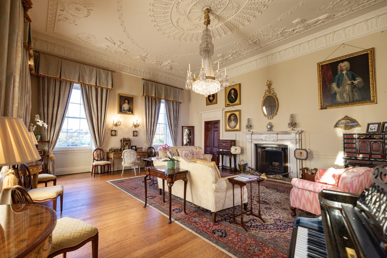 The Oval Drawing Room at Ripley Castle with ornate ceiling mouldings and a crystal chandelier, offering glorious views over the lakes and deer park from this historic European castle's finest reception spaces