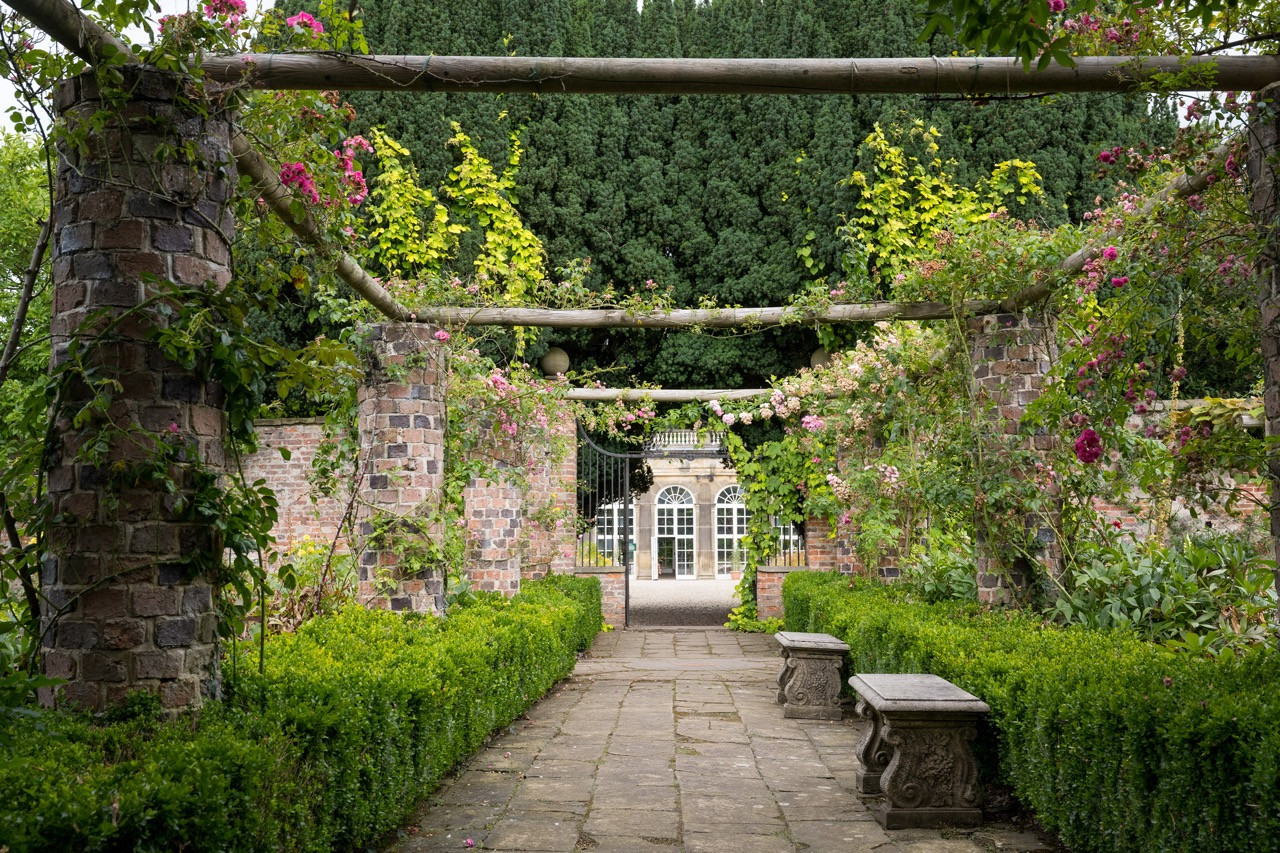 Rose garden pathway leading to The Orangery at Ripley Castle, part of the variety of Old English climbing roses and ornamental features within the extensive gardens of this historic European castle