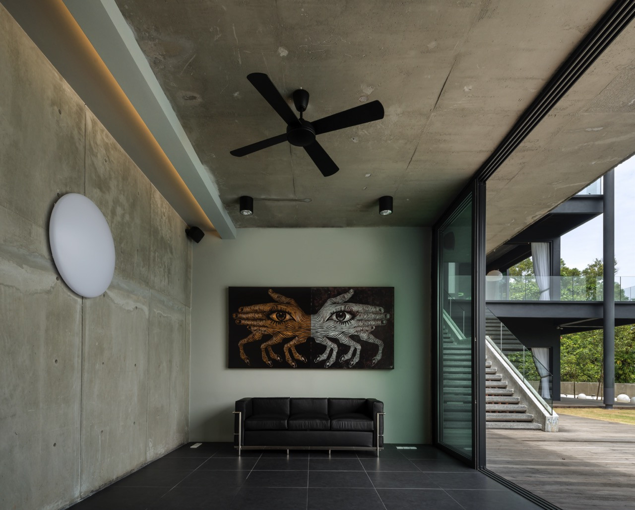 Lower level living area with exposed concrete ceiling, ceiling fans, and contemporary artwork opening to timber deck