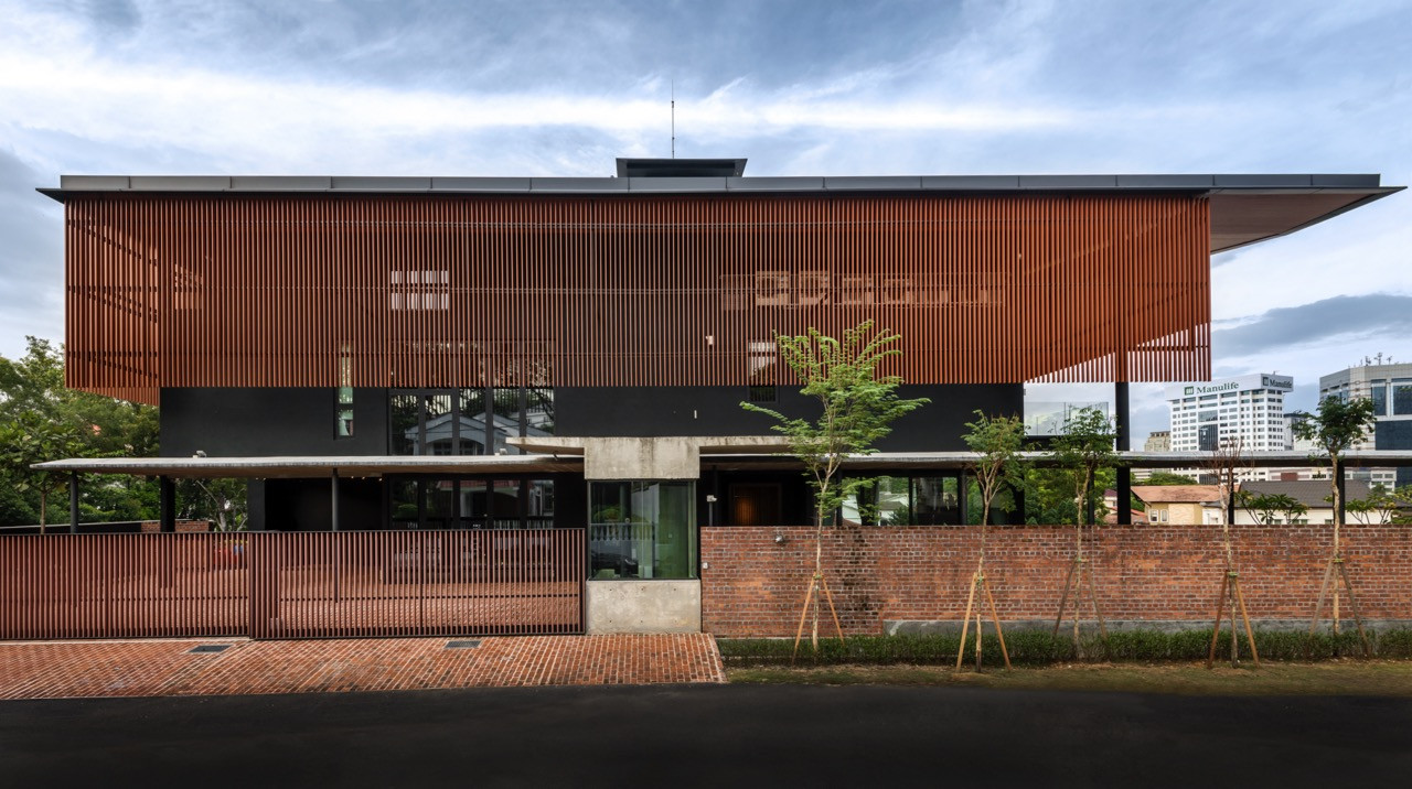 Street facade with extensive timber louvres, concrete elements, and clay brick boundary wall integration